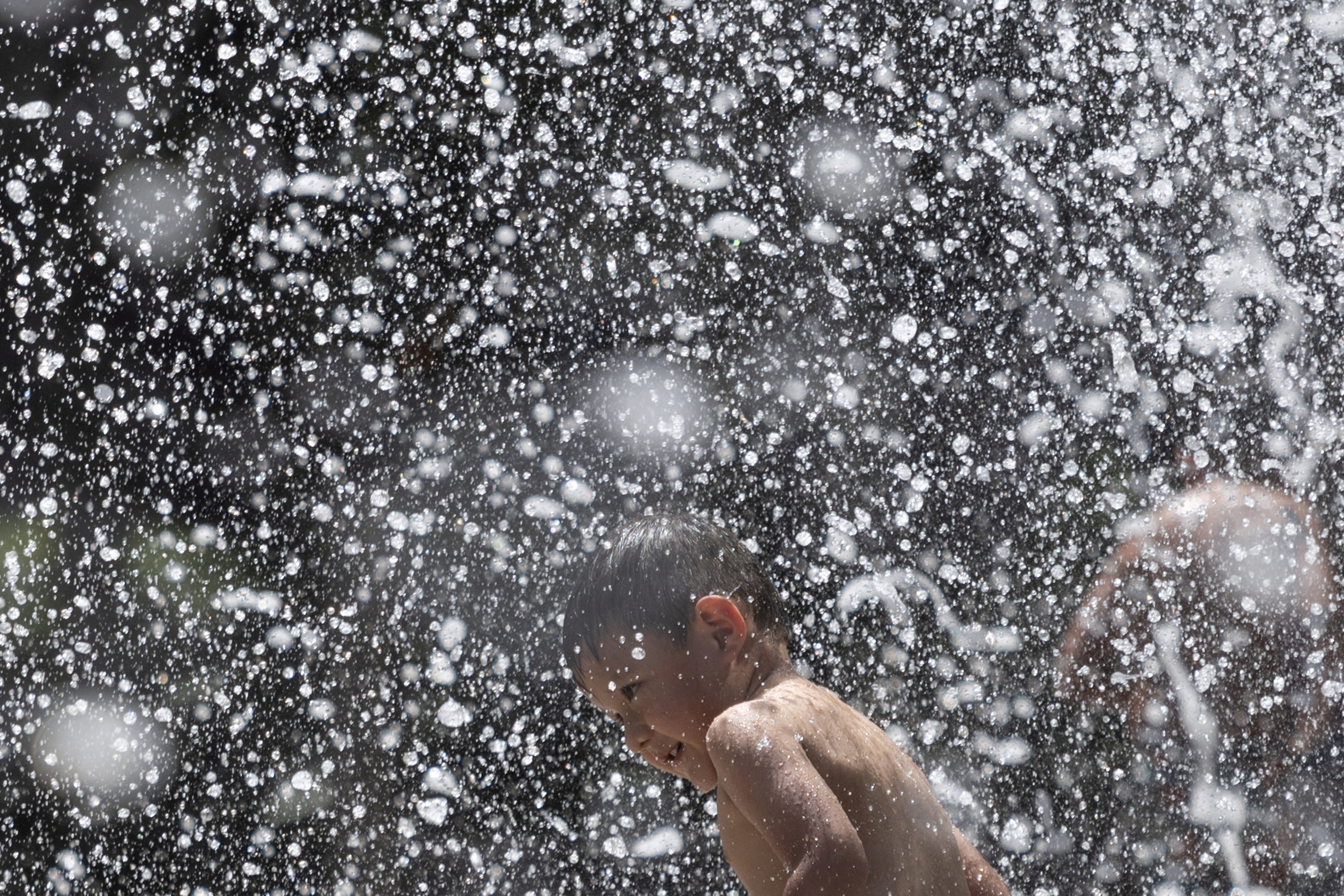 A young boy runs through the jet streams of Gateway Fountains at Discovery Green park to escape the hot weather in Houston, Texas, U.S., July 18, 2023. REUTERS/Adrees Latif