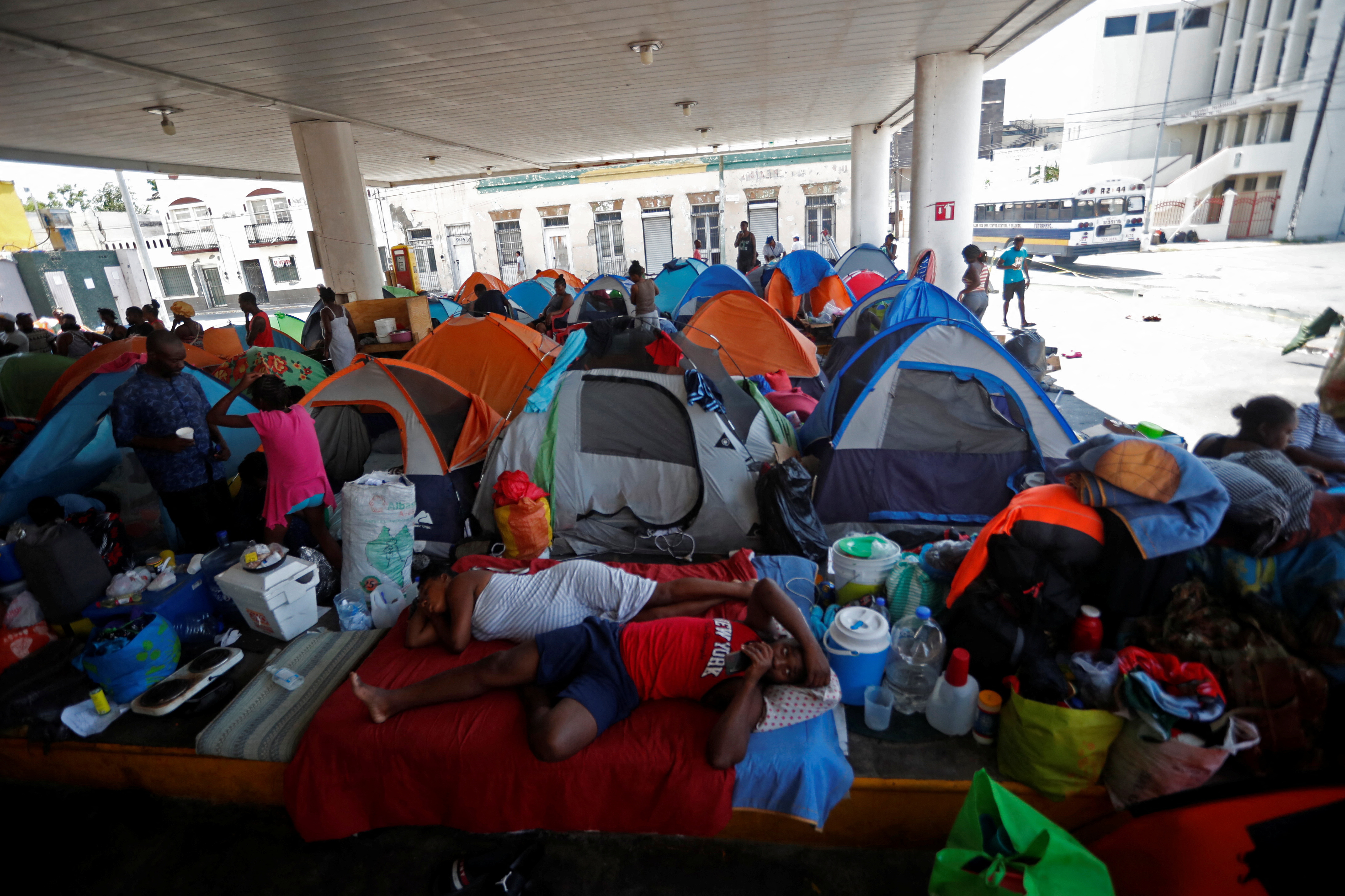 Haitian asylum seekers set up camp in an abandoned gas station while they wait to attempt to cross into the U.S. by an appointment through the Customs and Border Protection app, called CBP One, at a makeshift camp, in Matamoros, Mexico June 21, 2023. President Joe Biden promised to replace the hardline policies of former President Donald Trump, including the COVID-era public health order Title 42, with a more humane immigration system. The new Biden regulation allows migrants once again to ask for asylum at the border, but wait in Mexico for a slot on the app or risk a sped-up deportation process that could be conducted while they are held in detention. But in the first month of the new policy, Reuters found tens of thousands of people are waiting in dangerous Mexican border towns to snag a spot on the app, according to U.S. and Mexican officials, amid warnings from humanitarian groups of deteriorating sanitary conditions at migrant camps. REUTERS/Daniel Becerril