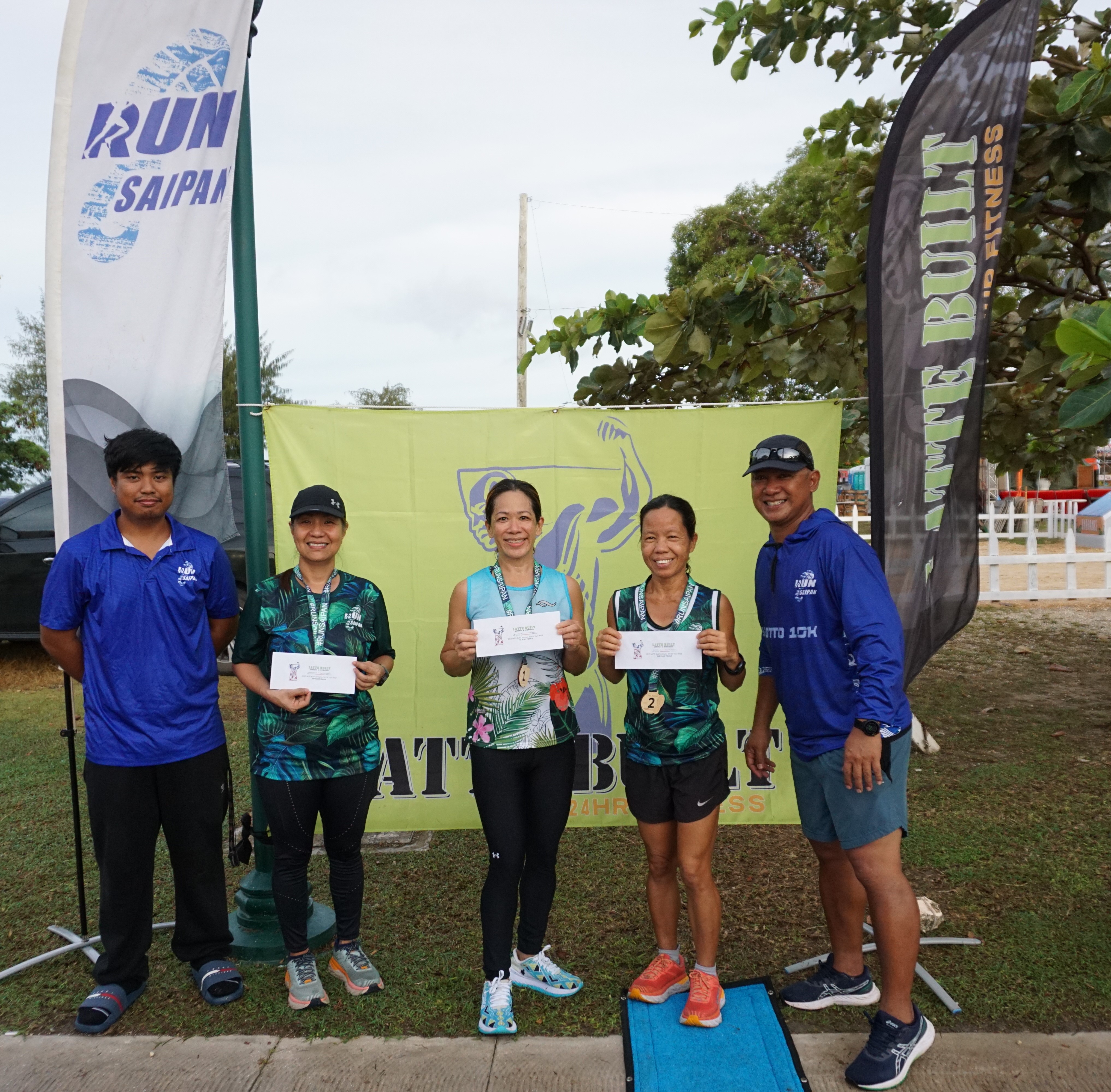 The top three women's division winners pose for a photo with Run Saipan tournament coordinator Simon Necesito and officer Robin Sapong during the awards ceremony for the 3rd Annual 4th of July Independence Day 2-Mile Run on Tuesday morning at the Garapan Fishing Base.