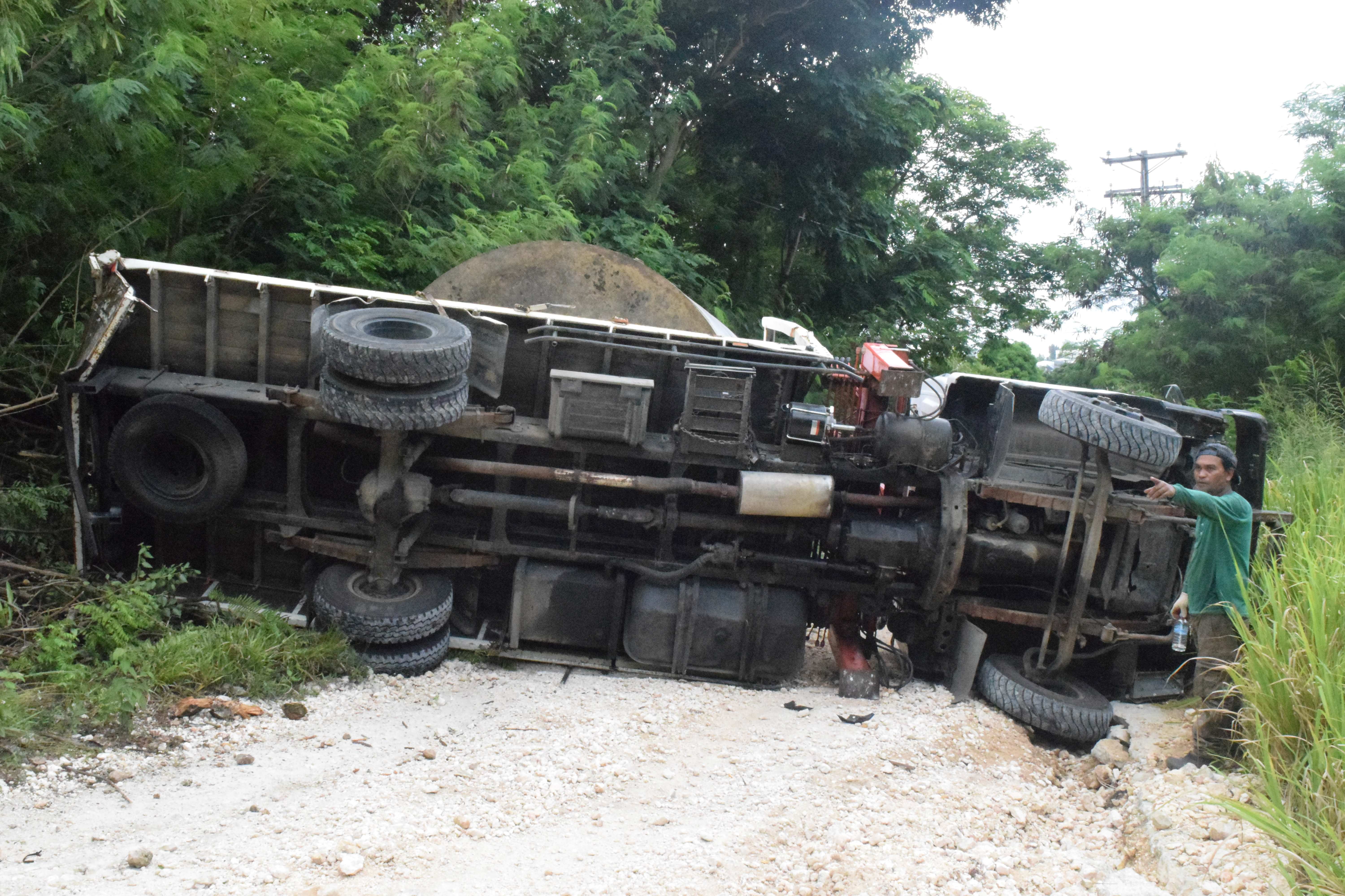 SG Auto Shop mechanic Remuel Maritano, right, points where the boom truck started skidding backwards before it overturned on Earhart Drive in Gualo Rai on Friday.