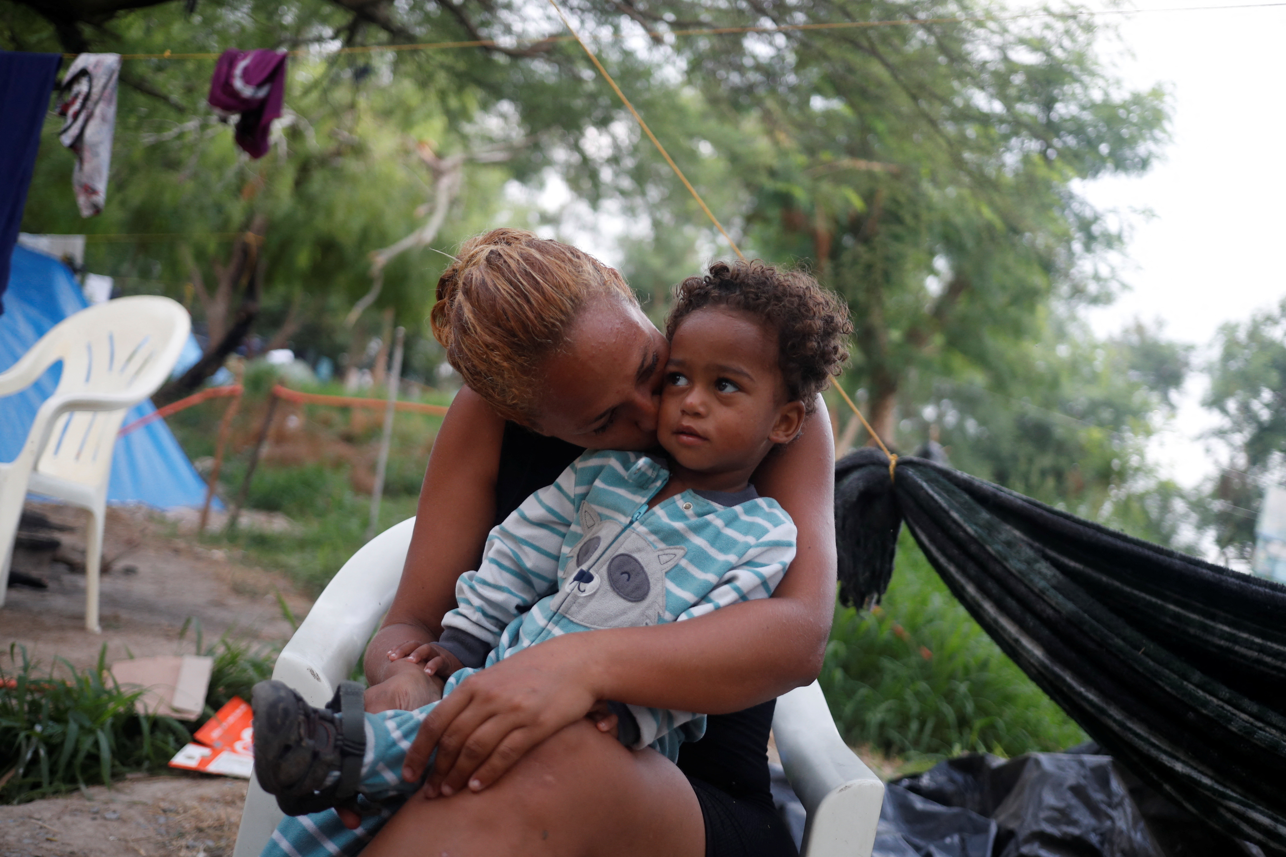 Venezuelan asylum seeker Alejandra Pena, 34, kisses her son Natanael, 1, next to their tent, while they wait to attempt to cross into the U.S. by an appointment through the Customs and Border Protection app, called CBP One, at a makeshift camp, in Matamoros, Mexico June 20, 2023. Pena fled Venezuela after a criminal group killed her sister, according to interviews and police records. Hoping to seek asylum in the United States, she said her family was stuck in northern Mexico because of new U.S. border rules adopted on May 11 by the administration of President Joe Biden. The rule requires migrants to make an appointment on a government-run smartphone app before approaching the border ? but none of the people with Pena has a device.?"We are paralyzed here," Pena said. REUTERS/Daniel Becerril