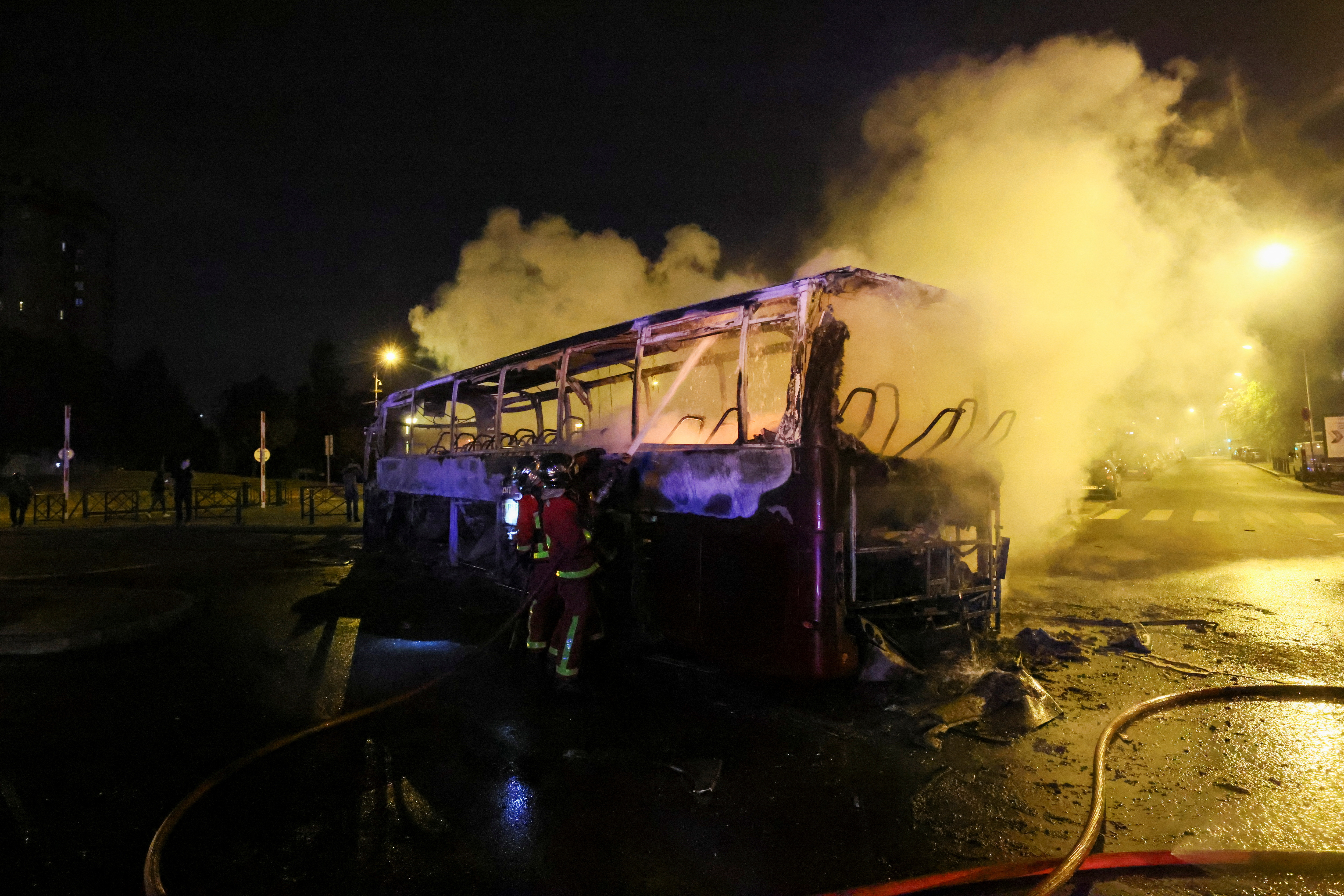Firefighters use a water hose on a burnt bus as unrest continues following the death of a 17-year-old teenager killed by a French police officer during a traffic stop, in Nanterre, Paris suburb, France, July 1, 2023. REUTERS/Yves Herman