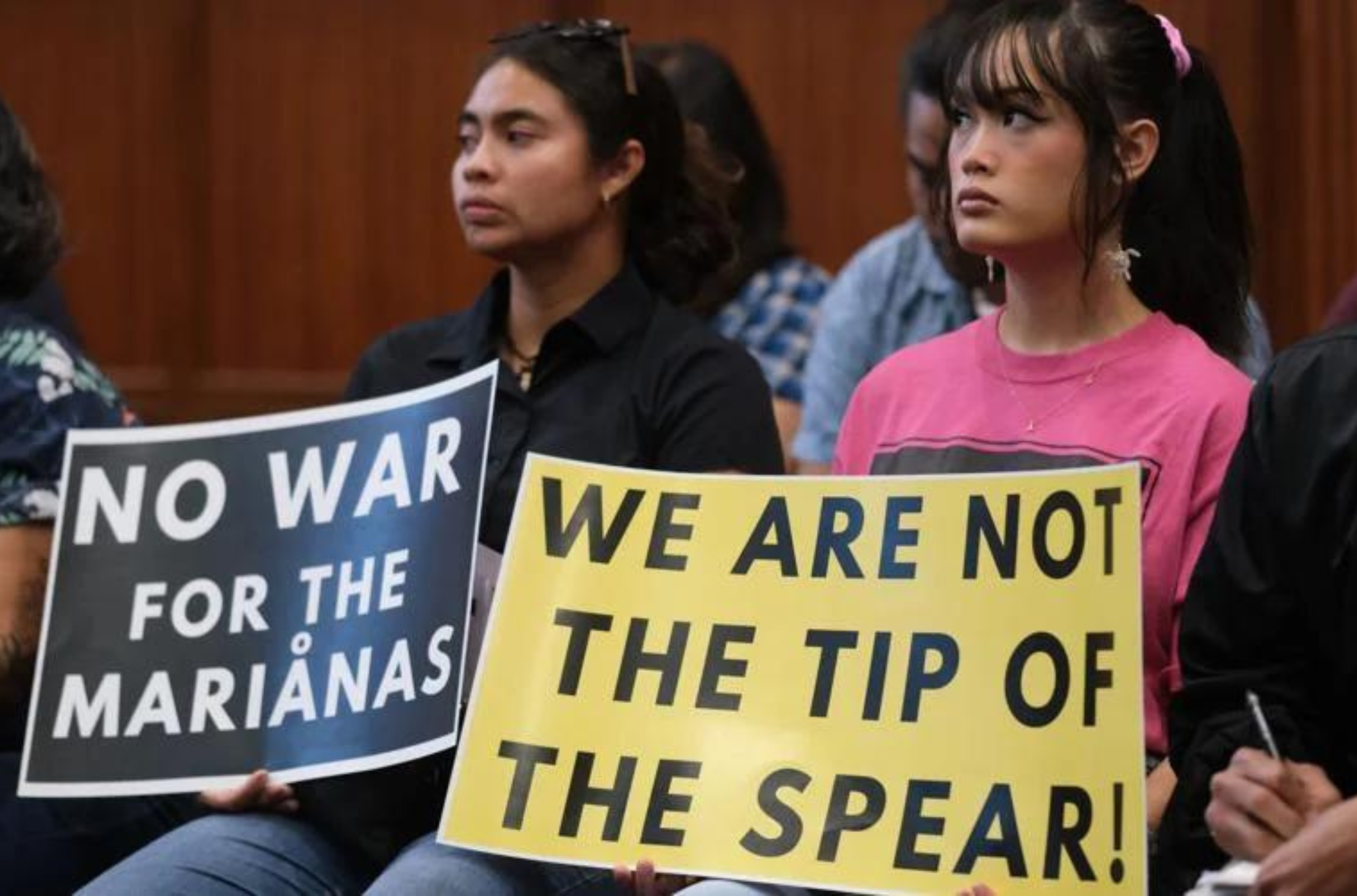 About a half-dozen people hold signs Monday, July 17, 2023, at the Public Hearing Room of the Guam Congress Building in Hagåtña during the legislative town hall on the proposed 360-degree missile defense system on Guam. 