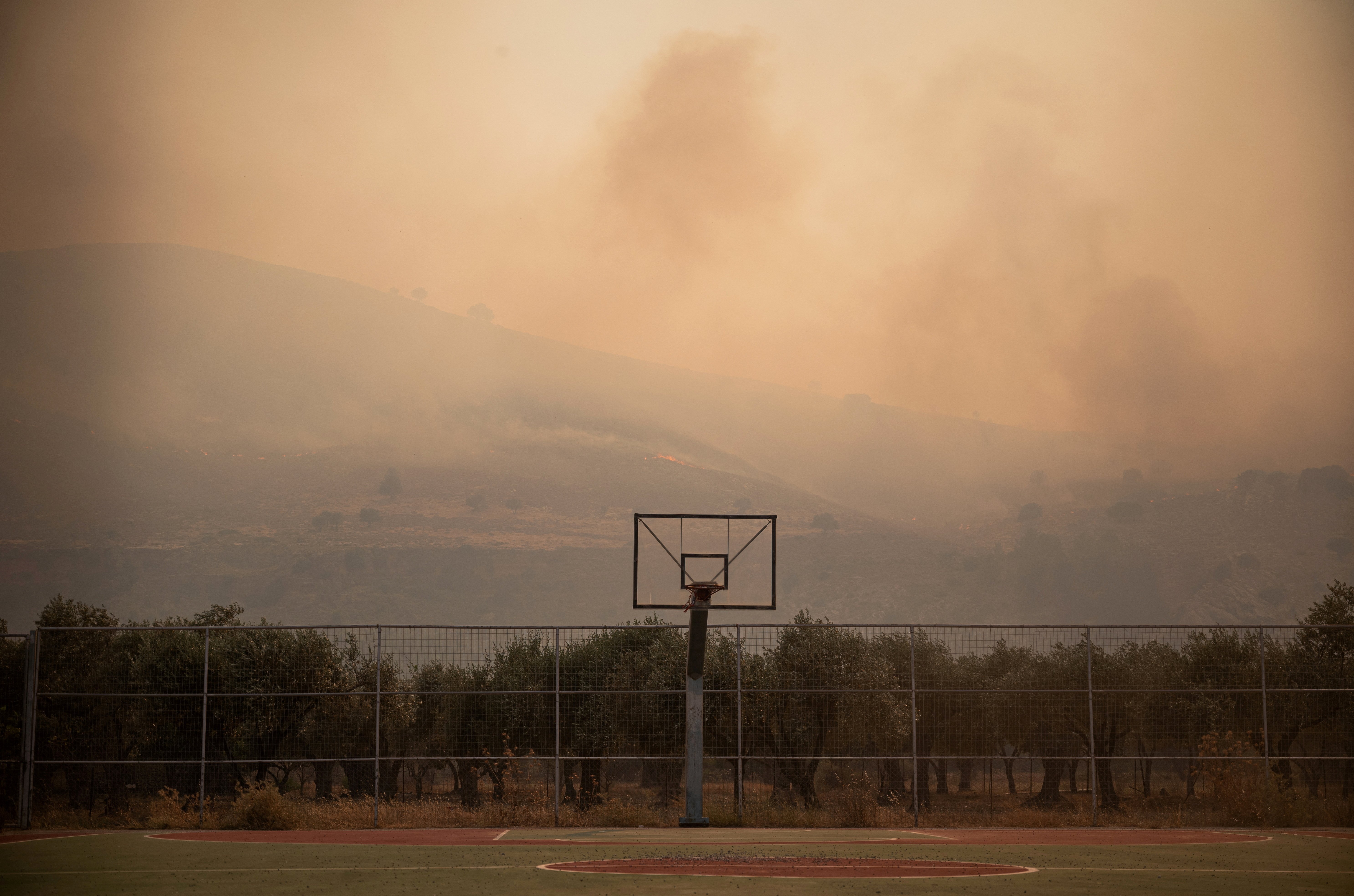 A smoke rising from a wildfire covers the air over a basketball court, near Lardos, on the island of Rhodes, Greece, July 22, 2023. REUTERS/Vassilis Ikoutas