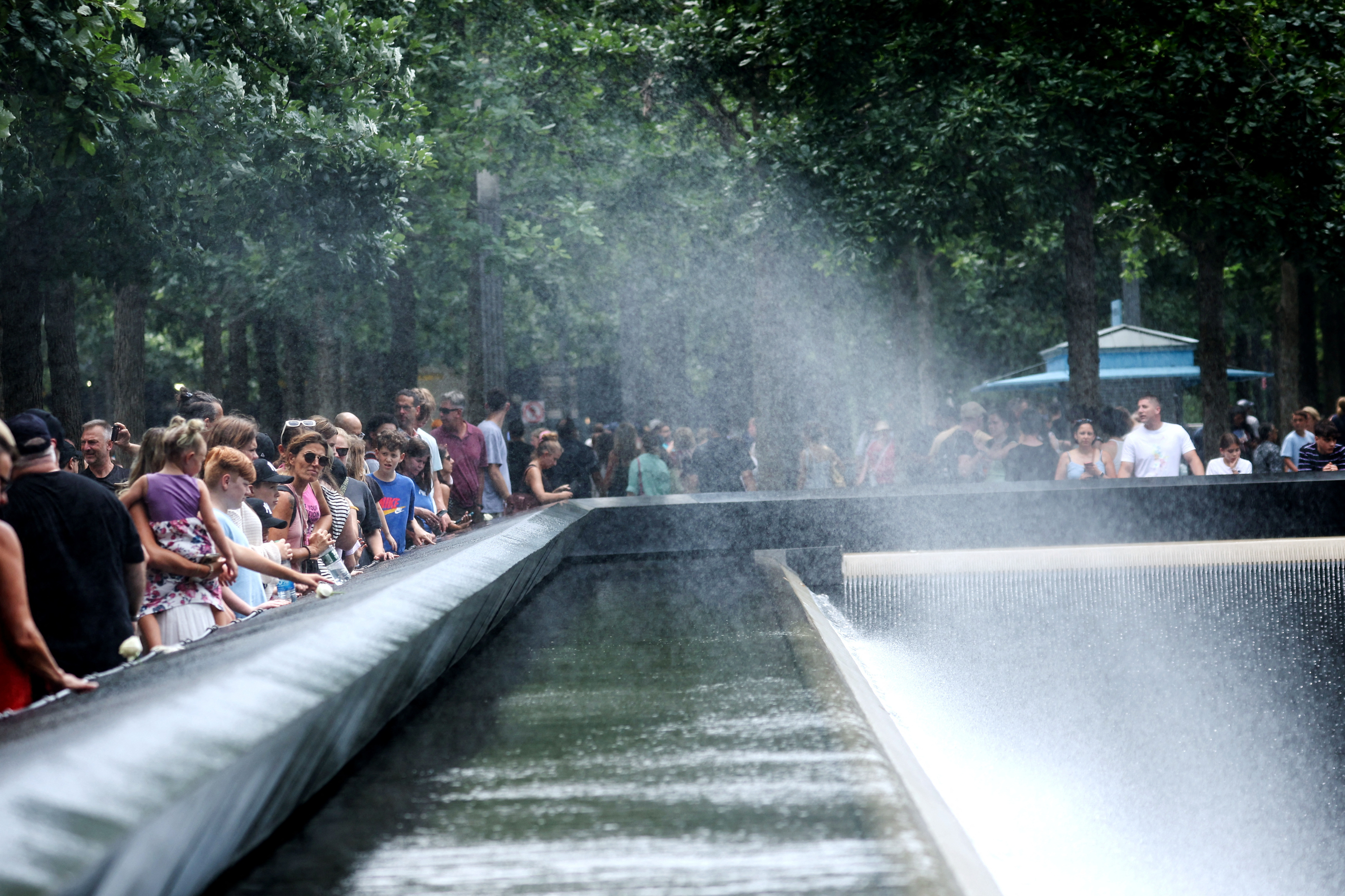 People cool off with a spray from the north reflecting pool, at the 911 Memorial and Museum, during hot windy weather in lower Manhattan in New York City, New York, U.S., July 27, 2023. REUTERS/Mike Segar