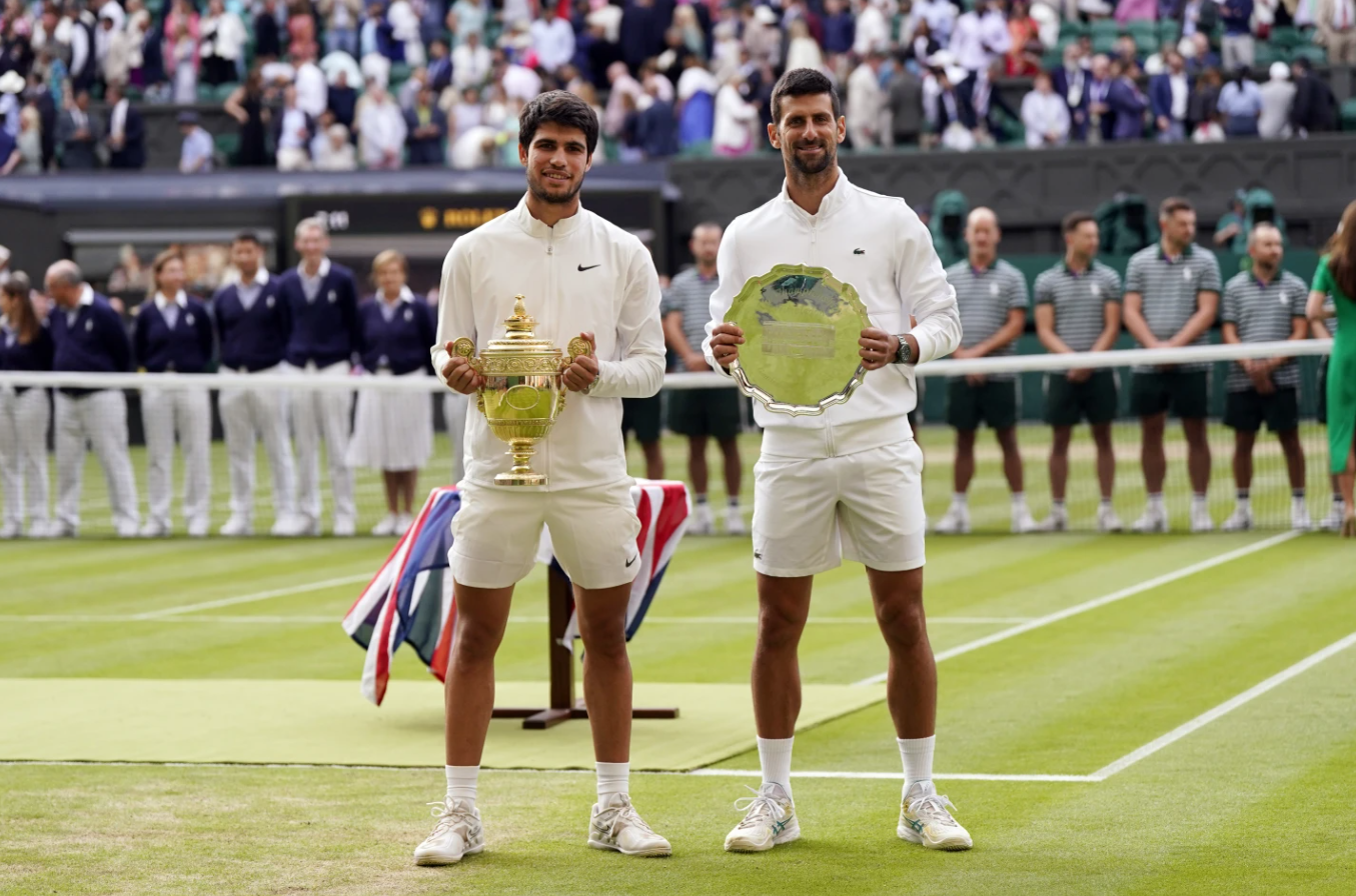 Spain’s Carlos Alcaraz, left, holds his trophy after beating Serbia’s Novak Djokovic, right, in the men’s singles final of the Wimbledon tennis championships in London, Sunday, July 16, 2023.