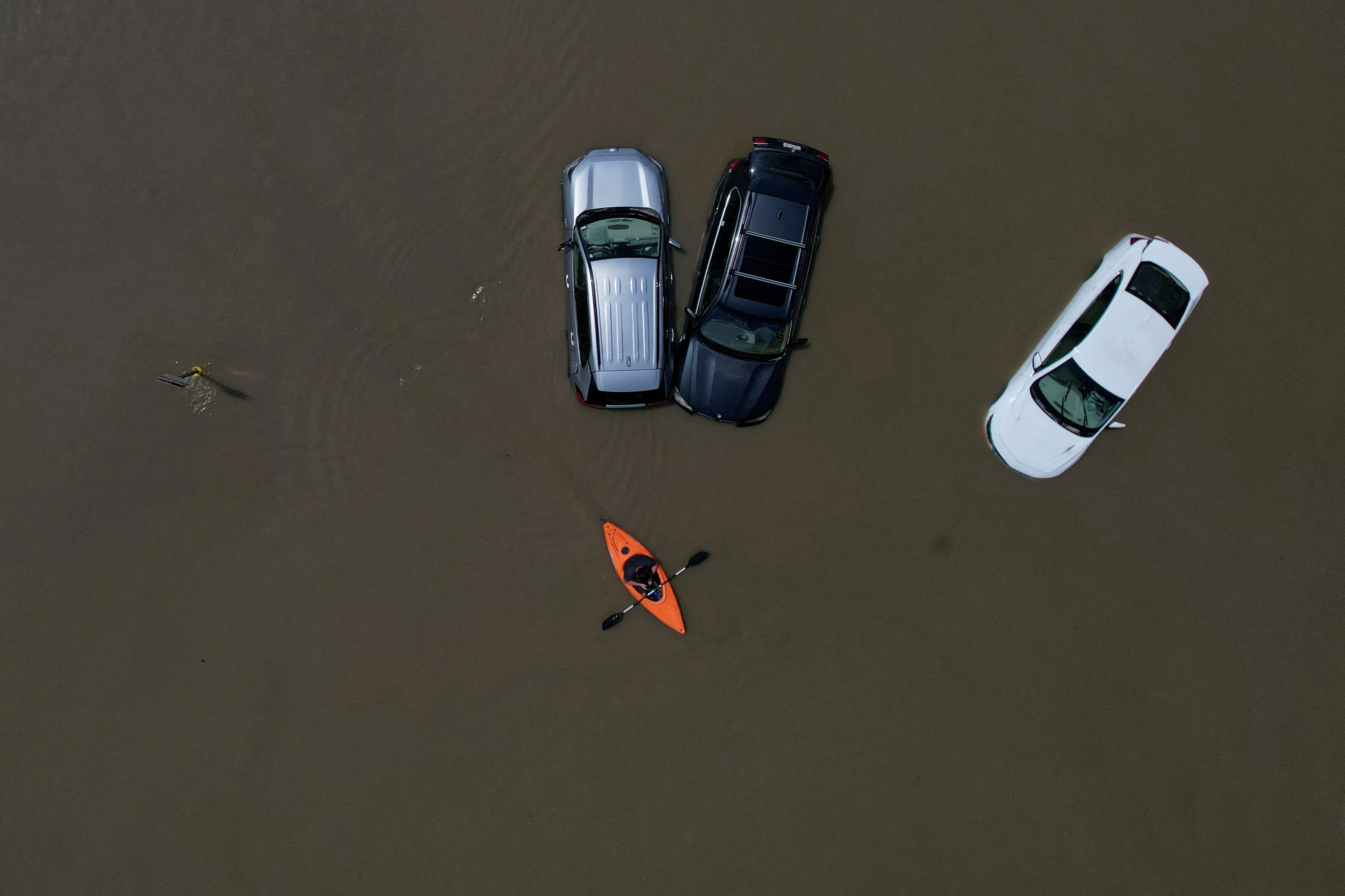 A person in a canoe passes cars partially submerged by flood waters from recent rain storms in Montpelier, Vermont, U.S., July 11, 2023. REUTERS/Brian Snyder/File Photo