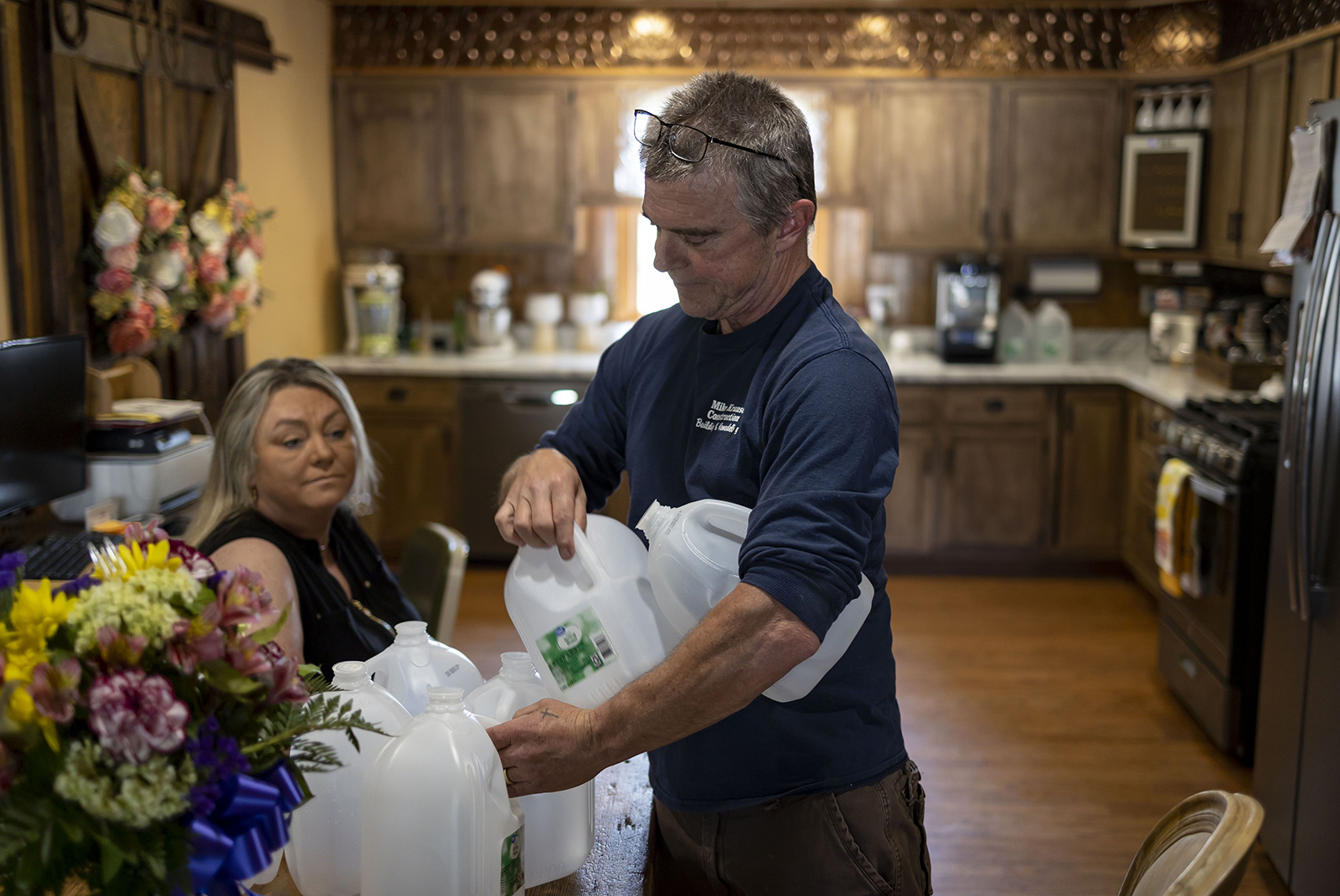 Mike Krause picks up some of the empty jugs he and his wife Kacy buy for drinking water, June 22, 2023, in Rockton. The Krauses, who live near the site of the 2021 Chemtool factory fire, now drink only bottled water after testing of their well water found toxic chemicals. (Brian Cassella/Chicago Tribune/TNS)
