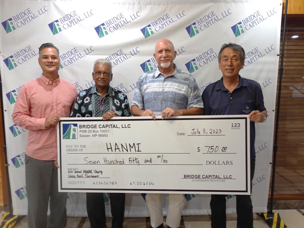Bridge Capital LLC Vice President/GM Bartley Jackson, second right, presents $750 cash on July 11, 2023, in support of the 21st Annual HANMI Charity Classic Golf Tournament, slated for July 15, 2022, at LaoLao Bay Golf & Resort.  From left, Bridge Capital Community Relations and Property Acquisitions Specialist Alex Palacios, tournament committee member Das Krishnan, Jackson, and tournament committee chairman Juko Ishikawa.