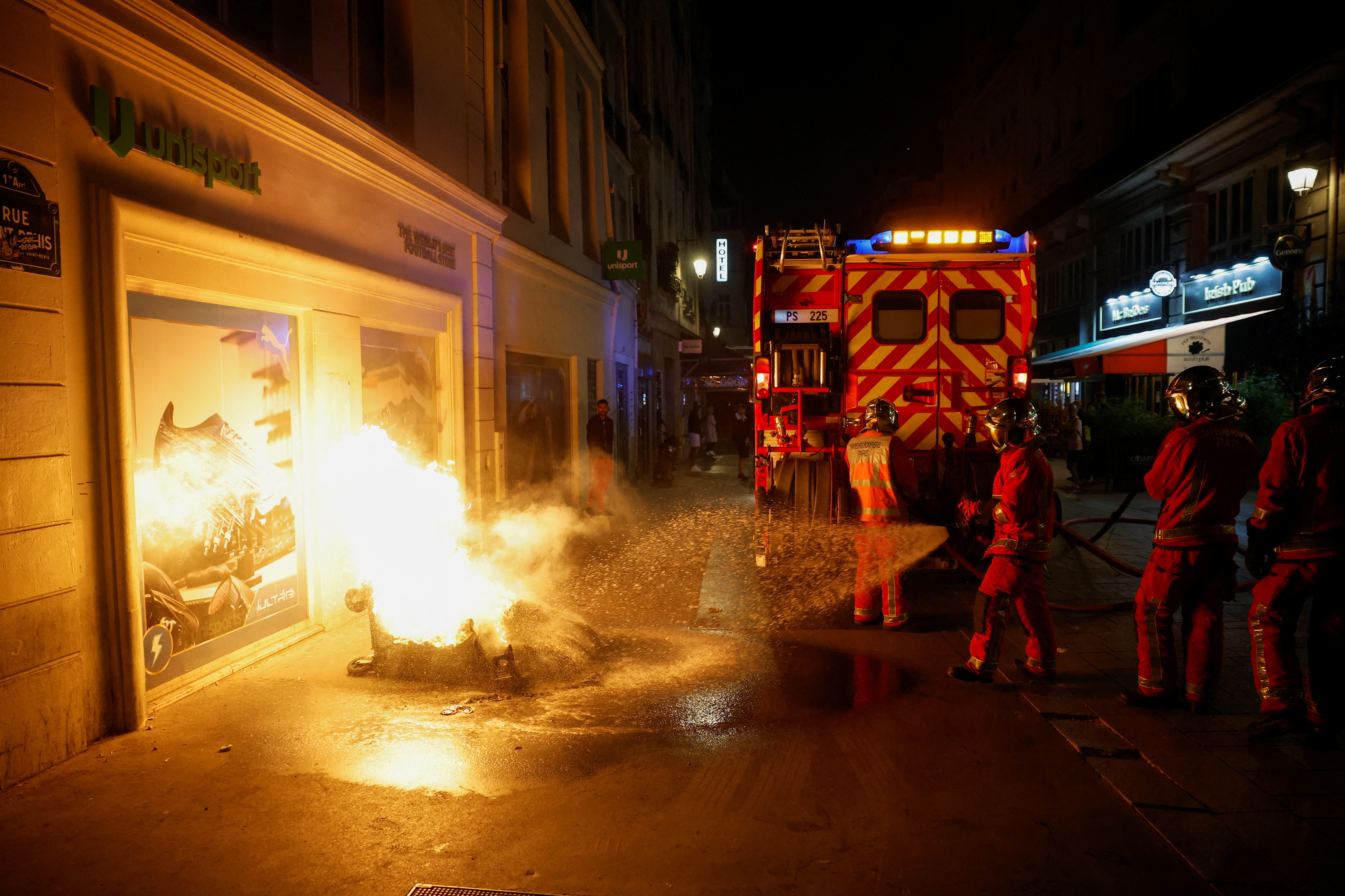 Firefighters work to extinguish a burning container as unrest continues following the death of Nahel, a 17-year-old teenager killed by a French police officer in Nanterre during a traffic stop, and against police violence, in Paris, France, July 1, 2023. REUTERS/Juan Medina