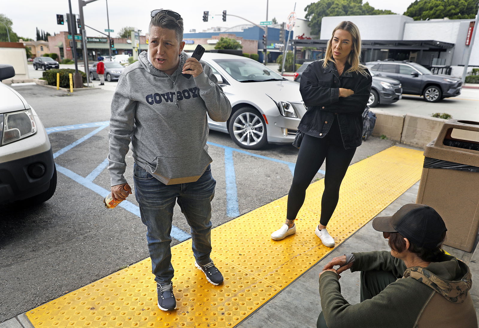 Crisis interventionist Vicki Lucas, left, is accompanied by Emily Spencer, middle, who works for Lucas on a freelance basis-part of a larger network of assistants that Lucas maintains for intervention work throughout the state and the country, as they provide Sherry Hillâ€™s daughter, right, with a chance to speak on a phone with Hill outside of a 7-Eleven convenience store in Pasadena, California, on May 11, 2023. (Christina House/Los Angeles Times/TNS)