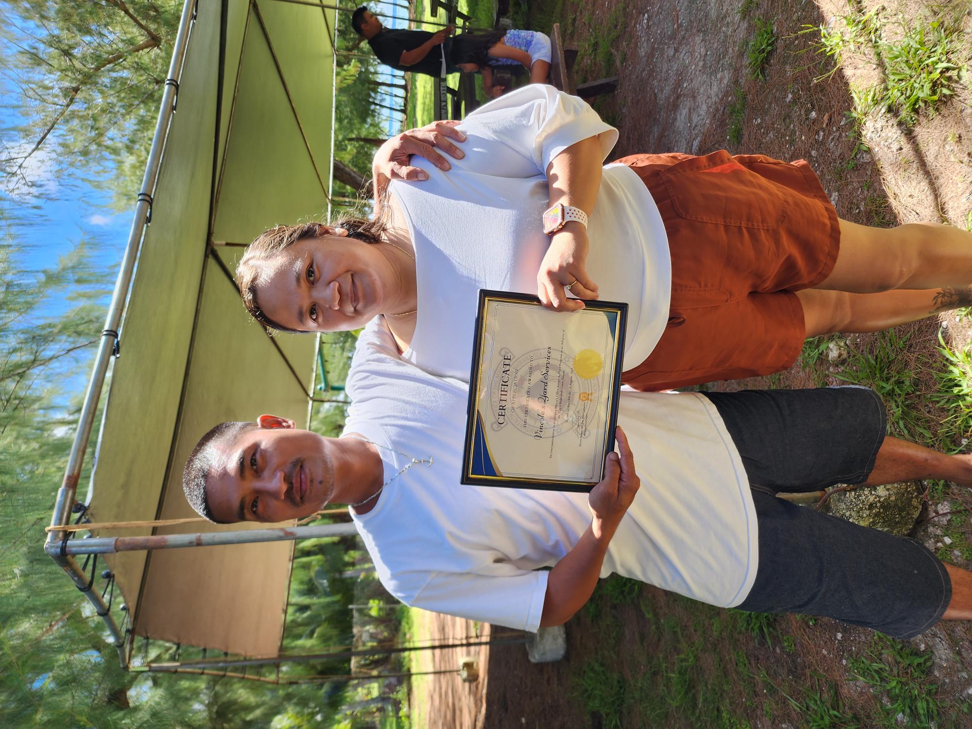 Vincent Norita and Nicole Deleon Guerrero of Vincole Lawncare Services hold a certificate of appreciation from Saipan Mayor Ramon "RB" Camacho for officially adopting the Laly 4 basketball court in Chalan Kanoa.