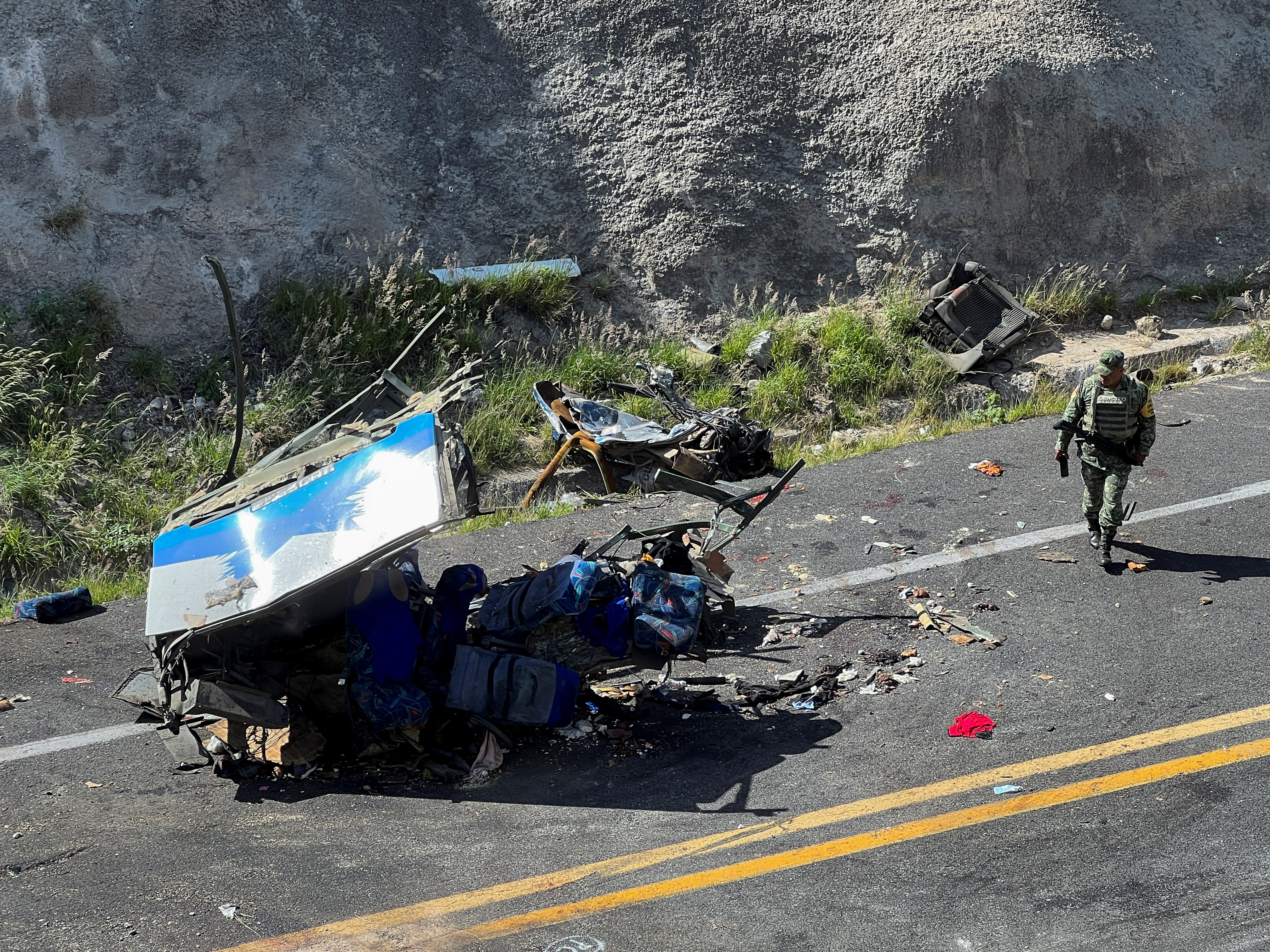 A soldier walks by a part of the wreckage of a bus at the area of a road accident, which left over a dozen migrants dead, in Tepelmeme Villa de Morelos, in Oaxaca state, Mexico August 22, 2023. REUTERS/Jose de Jesus Cortes