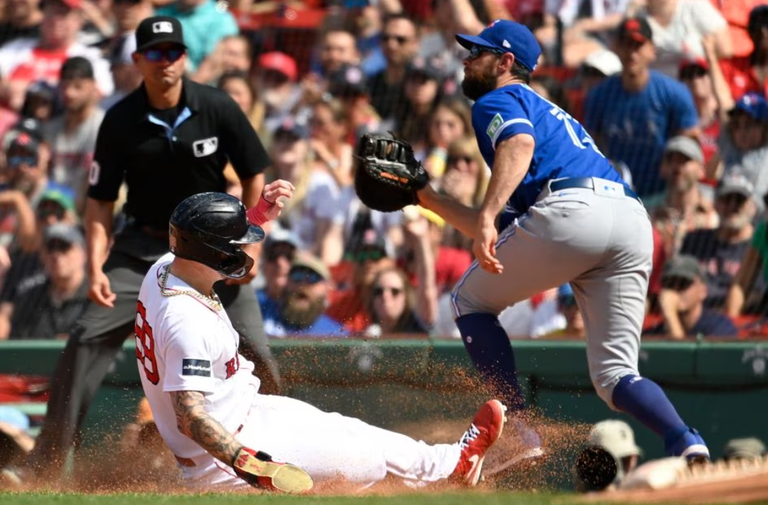 Boston Red Sox right fielder Alex Verdugo (99) slides into first base before the ball gets to Toronto Blue Jays first baseman Brandon Belt (13) during the sixth inning at Fenway Park in Boston, Massachusetts, Aug. 6, 2023.