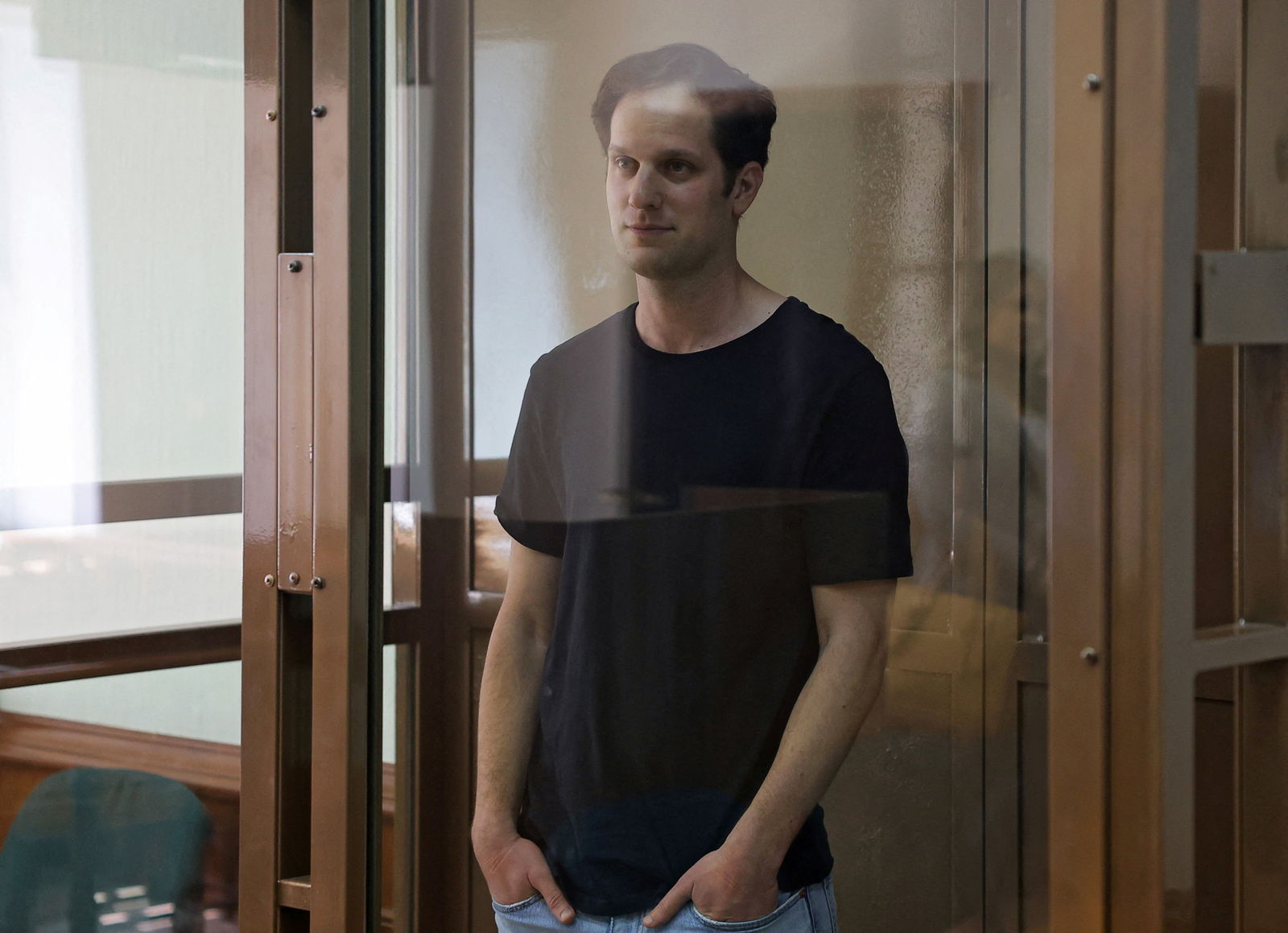 Wall Street Journal reporter Evan Gershkovich, who was arrested in March while on a reporting trip and accused of espionage, stands behind a glass wall of an enclosure for defendants before a court hearing to consider an appeal against his detention, in Moscow, Russia June 22, 2023. REUTERS/Evgenia Novozhenina