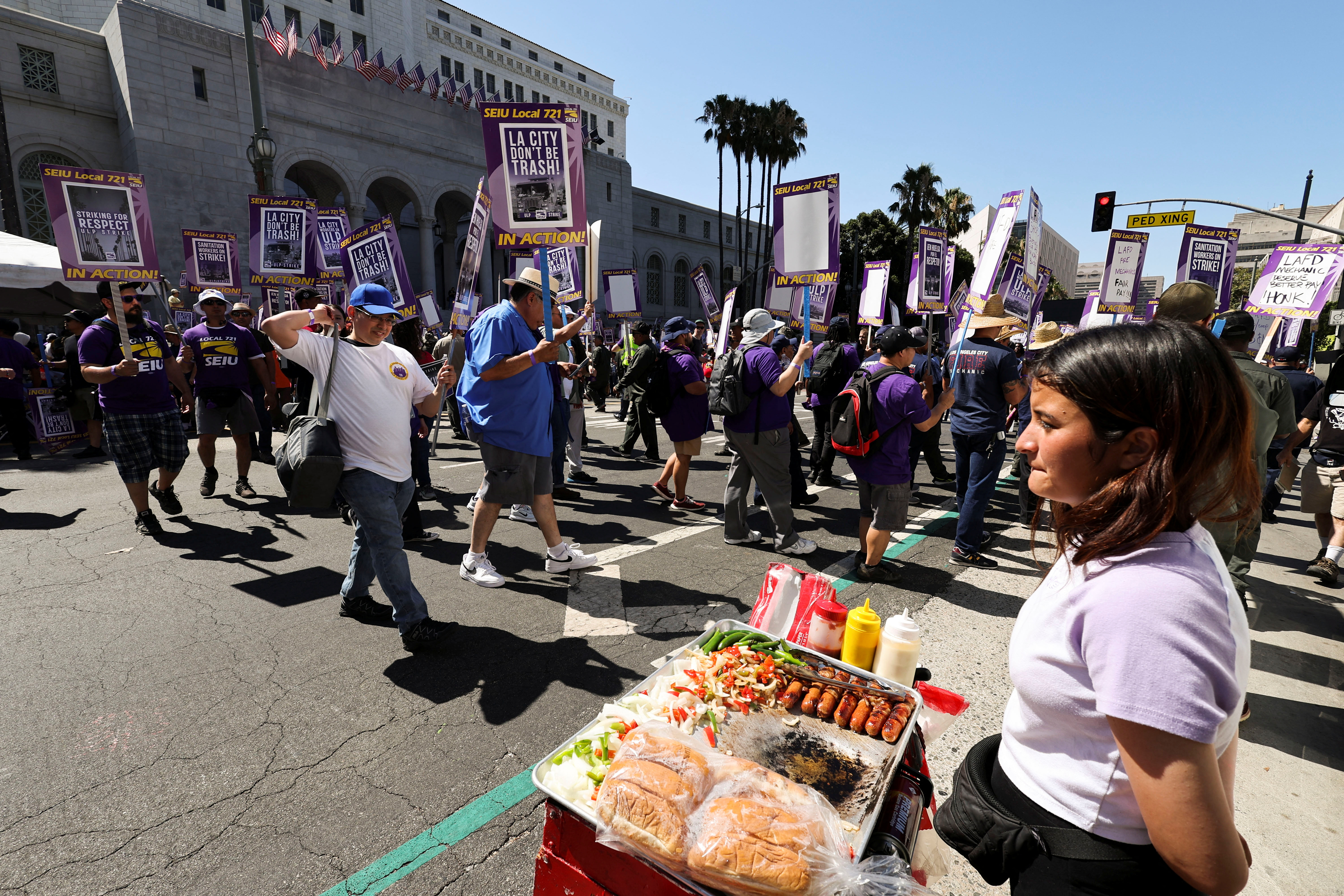 A street vendor looks on as Los Angeles city workers hold a rally during a one-day walkout strike in protest over labor negotiations, in Los Angeles, California, U.S., August 8, 2023. REUTERS/Mike Blake