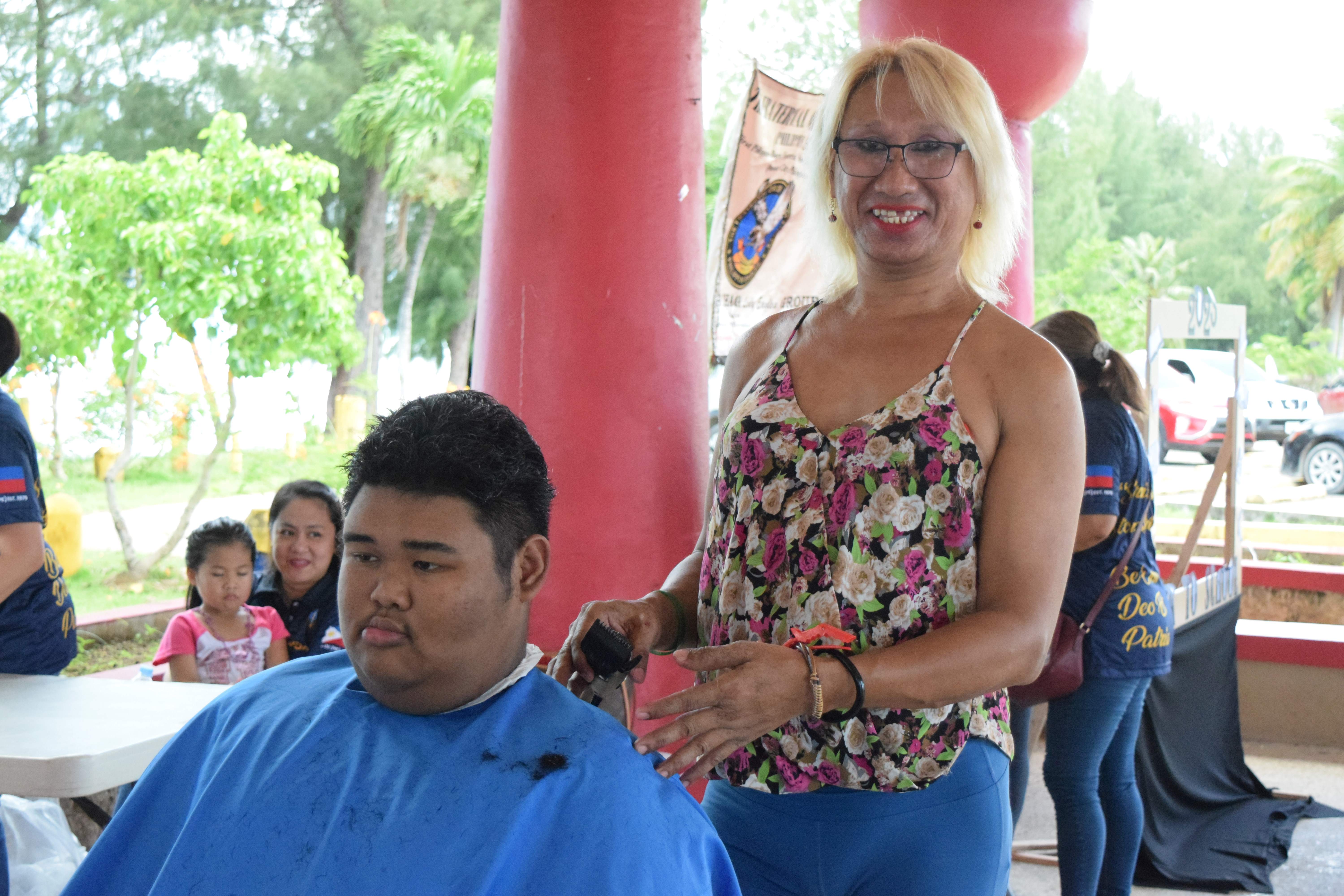 Hairstylist Linda Lumauag happily gives a boy a haircut.