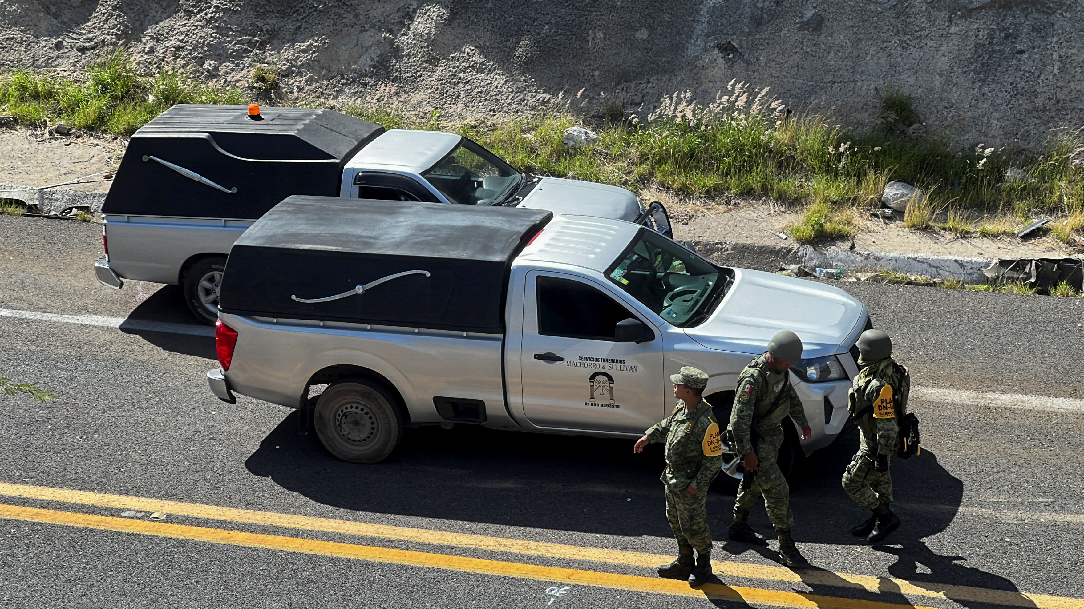 Soldiers stand next to funeral hearses at the area of a road accident, which left over a dozen migrants dead, in Tepelmeme Villa de Morelos, in Oaxaca state, Mexico August 22, 2023. REUTERS/Jose de Jesus Cortes