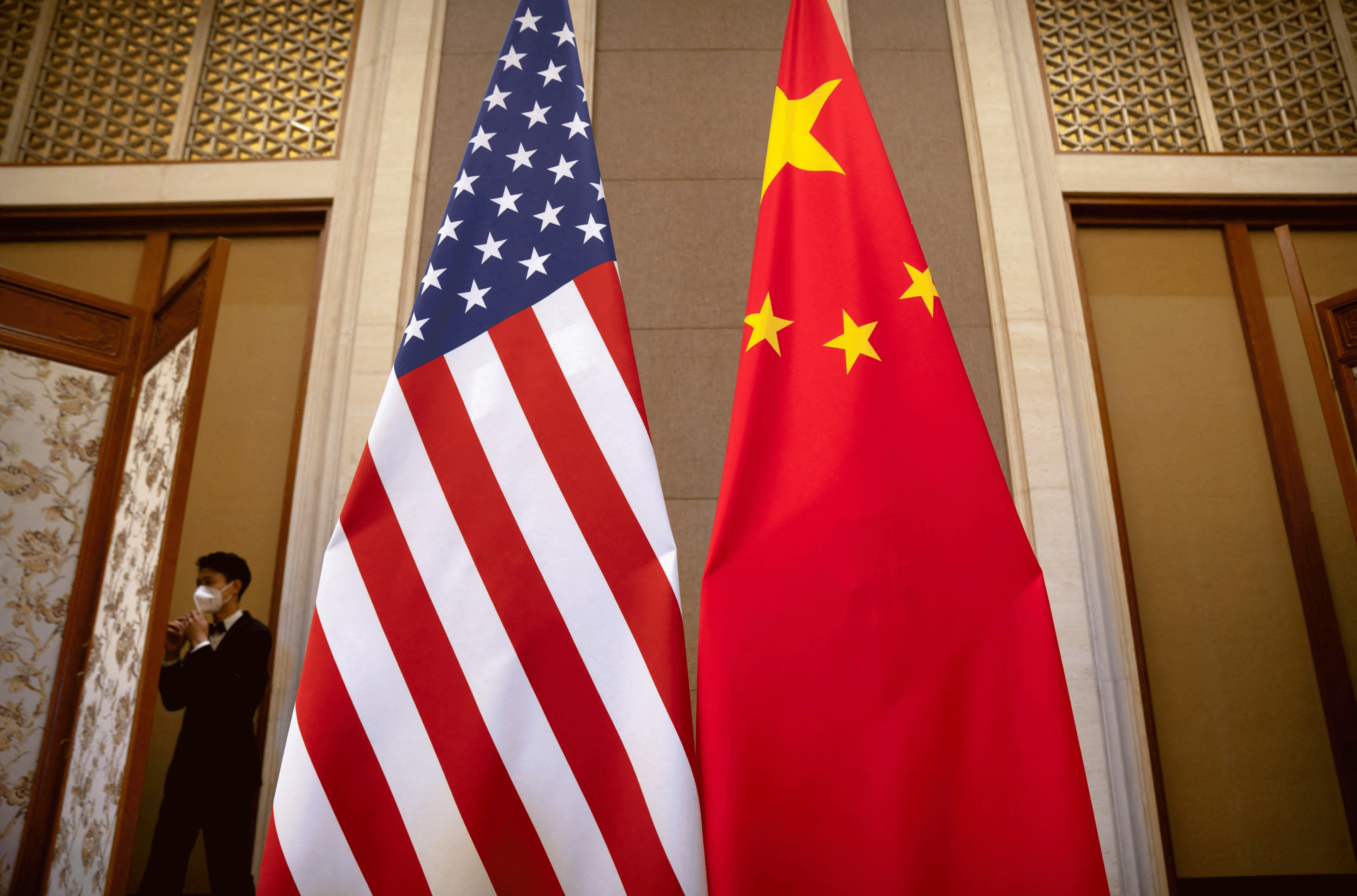 A staff member wearing a face mask walks past United States and Chinese flags set up before a meeting between Treasury Secretary Janet Yellen and Chinese Vice Premier He Lifeng at the Diaoyutai State Guesthouse in Beijing, China, Saturday, July 8, 2023. Mark Schiefelbein/Pool via REUTERS/File Photo