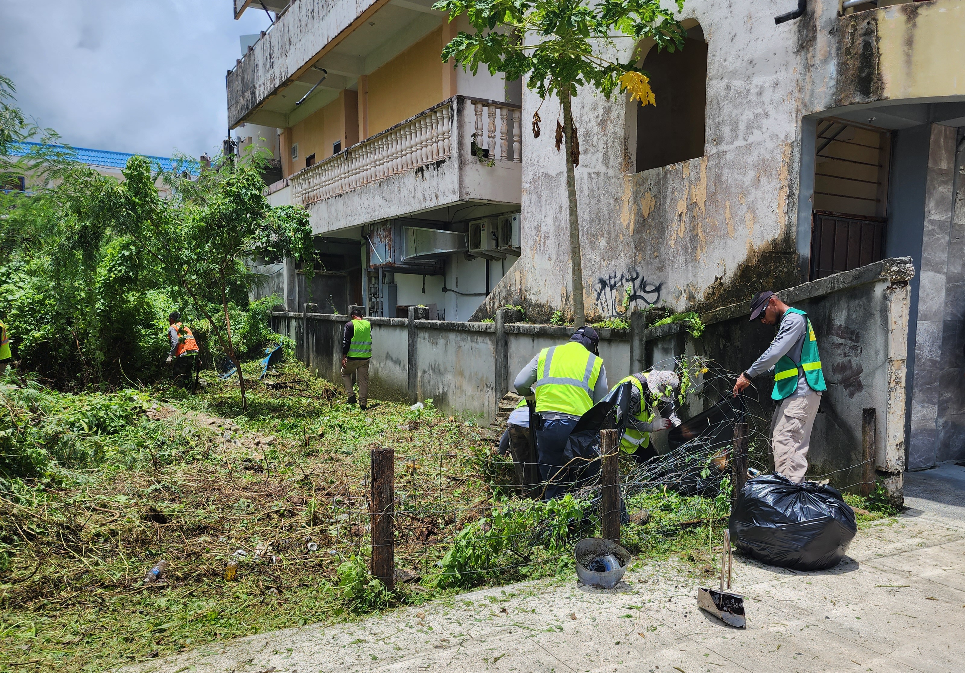 Inmates remove debris and overgrown vegetation from a private lot in Garapan across from the Hyatt on Wednesday.