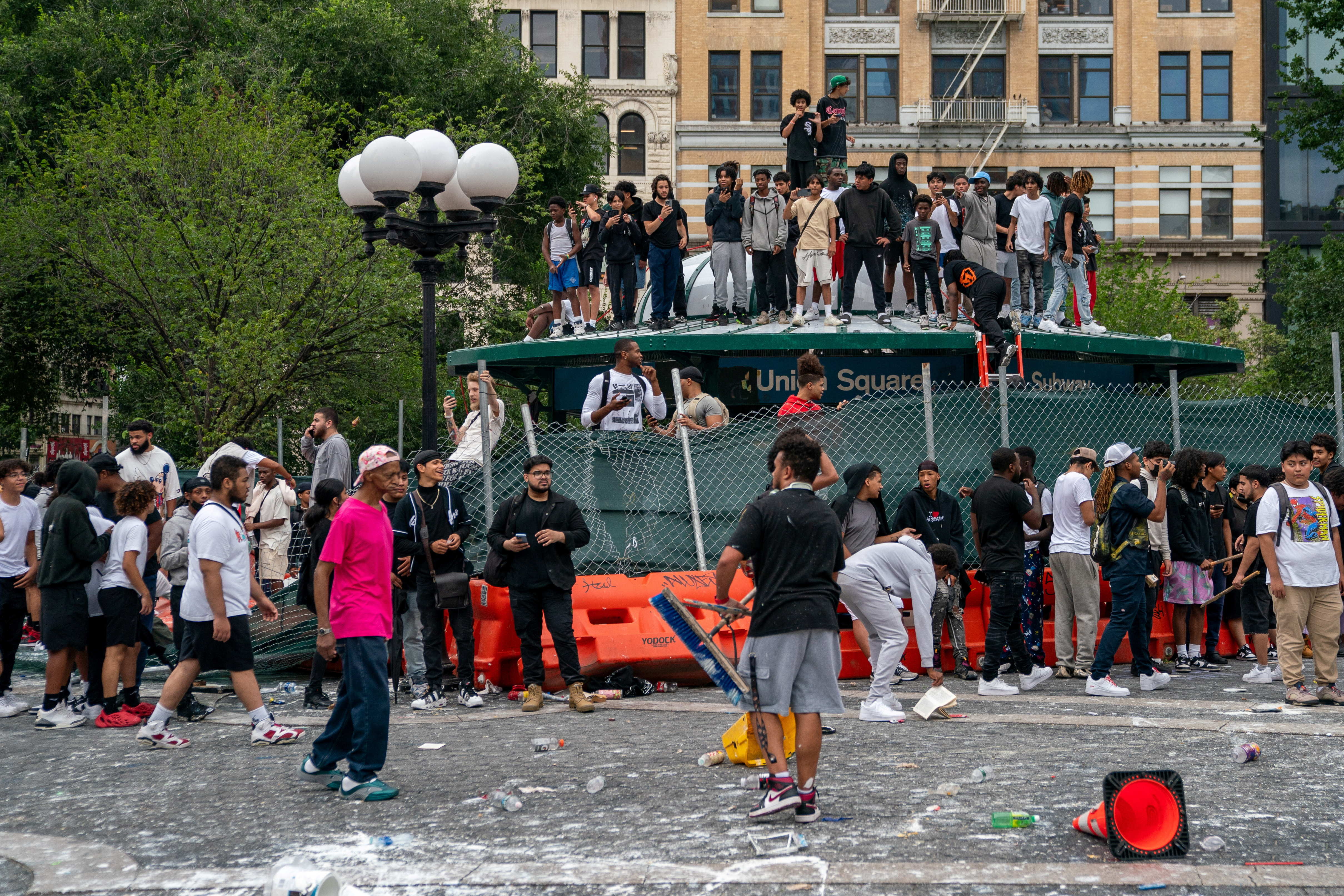 People stand on top of a subway station entrance to protect themselves after popular live streamer Kai Cenat announced a "giveaway" event that grew chaotic, prompting police officers to respond and disperse the crowd at Union Square and the surrounding streets, in New York City, U.S. August 4, 2023. REUTERS/David 'Dee' Delgado