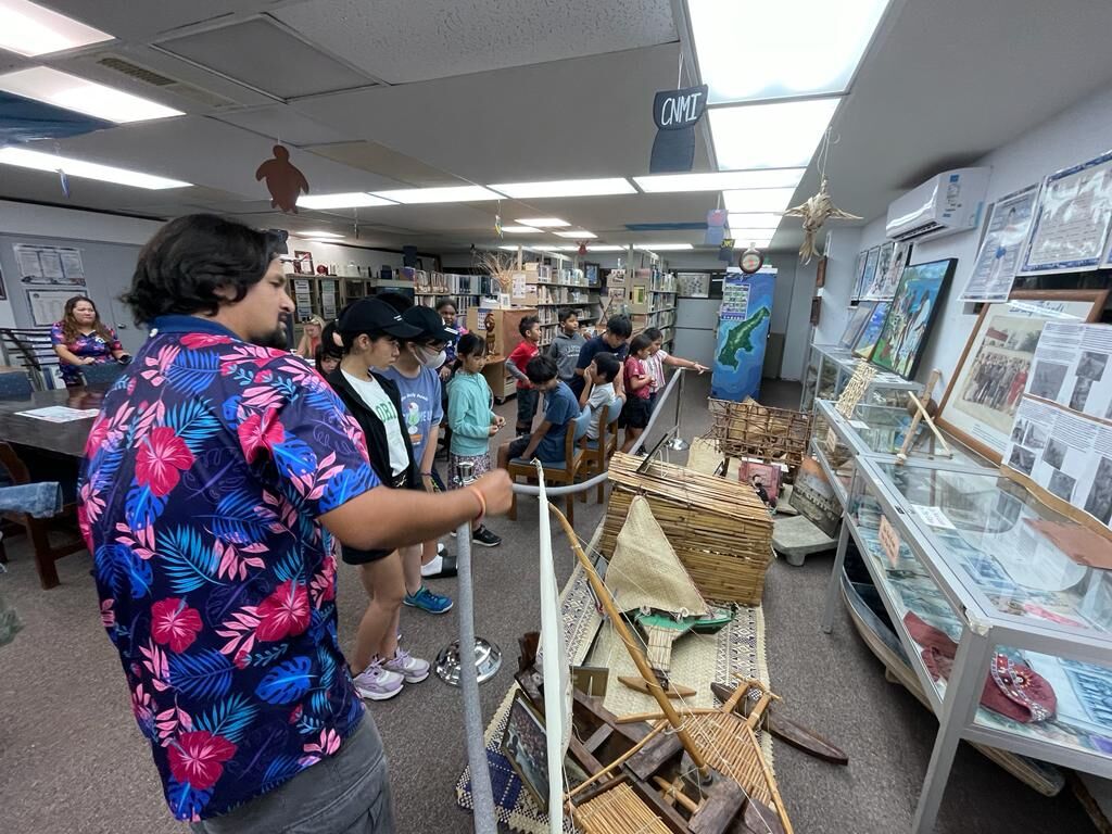 The students are shown historical exhibits at the Joeten Kiyu Public Library by its staff.