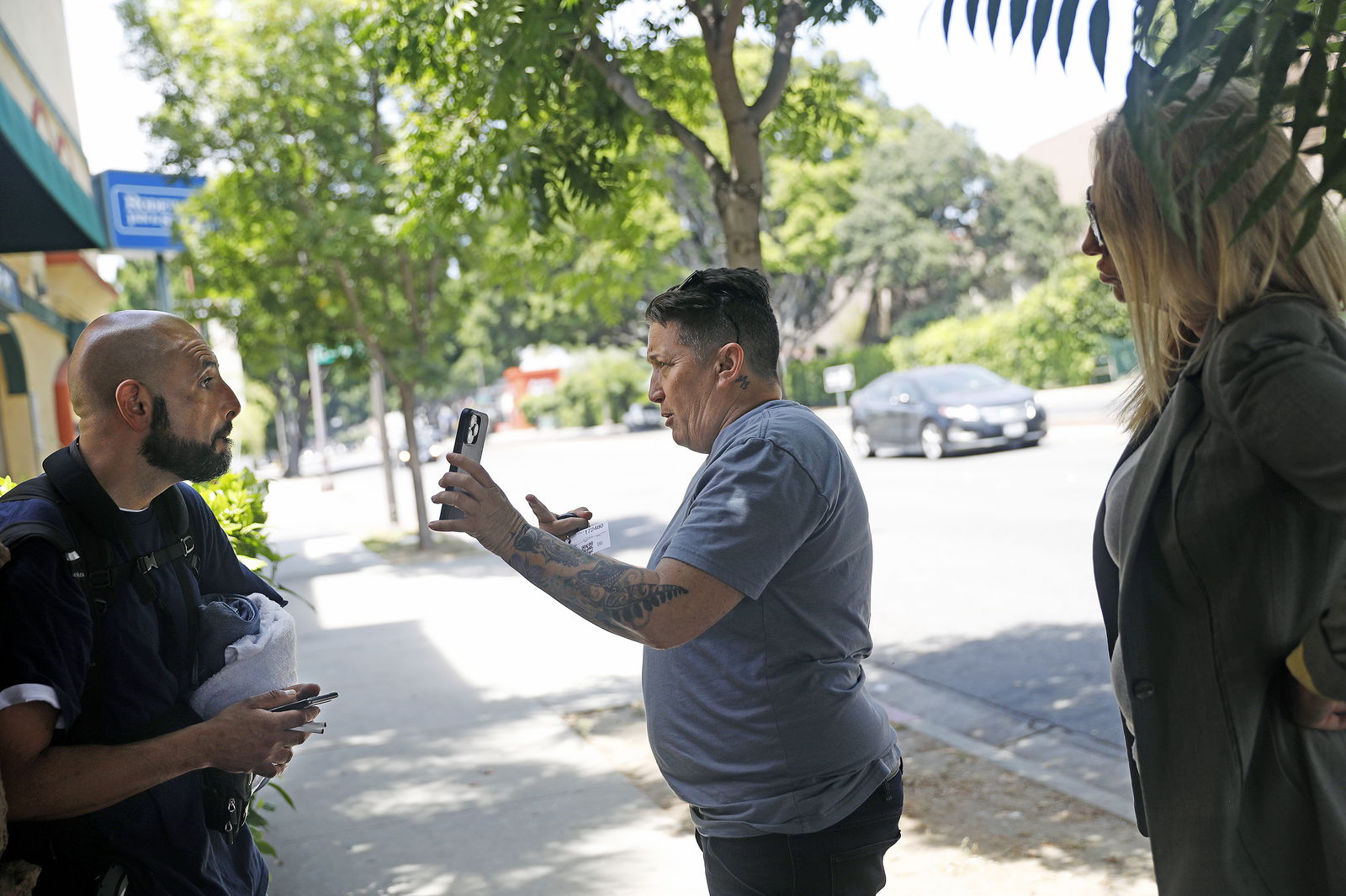 Crisis interventionist Vicki Lucas, center, shows a photo of Sherry Hillâ€™s daughter to Jesus Franco, left, standing outside of a motel in Pasadena, California, hoping he could provide information that could lead to locating her, on July 21, 2023. (Christina House/Los Angeles Times/TNS)