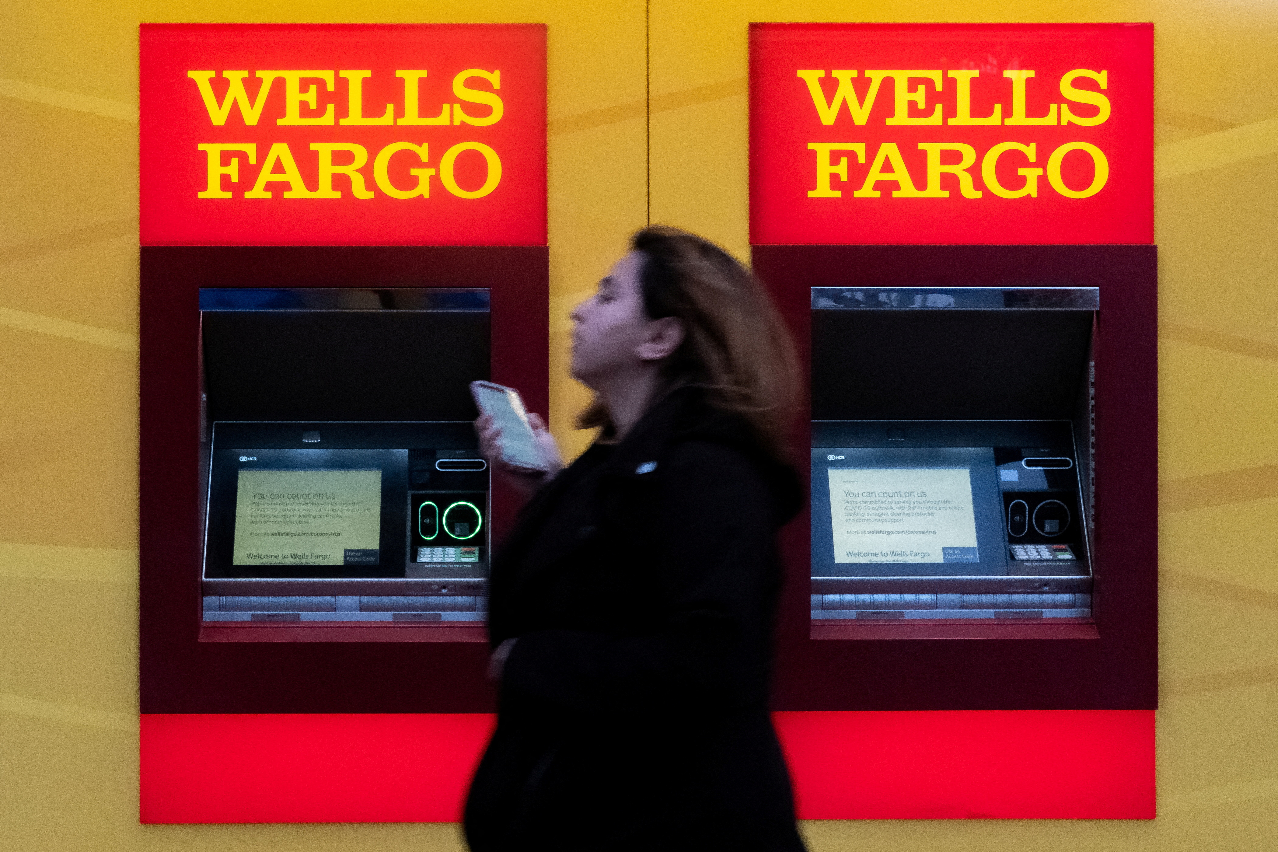 A woman walks past Wells Fargo bank in New York City, U.S., March 17, 2020. REUTERS/Jeenah Moon/File Photo
