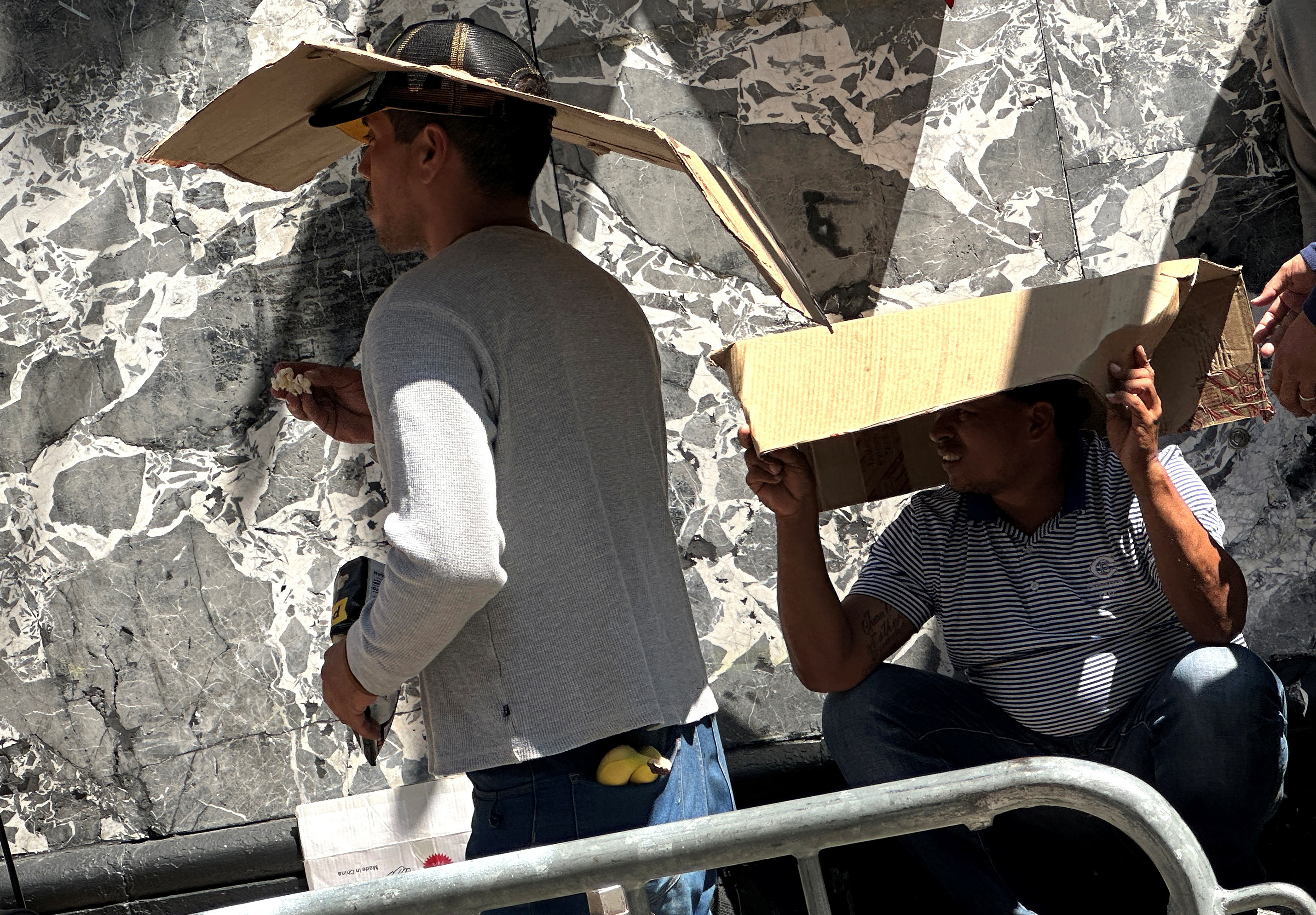 Recently arrived migrants to New York City shade themselves from the sun as they crowd together while waiting on the sidewalk outside the Roosevelt Hotel in midtown, Manhattan, where a temporary reception center has been established in New York City, New York, U.S., August 1, 2023. REUTERS/Mike Segar