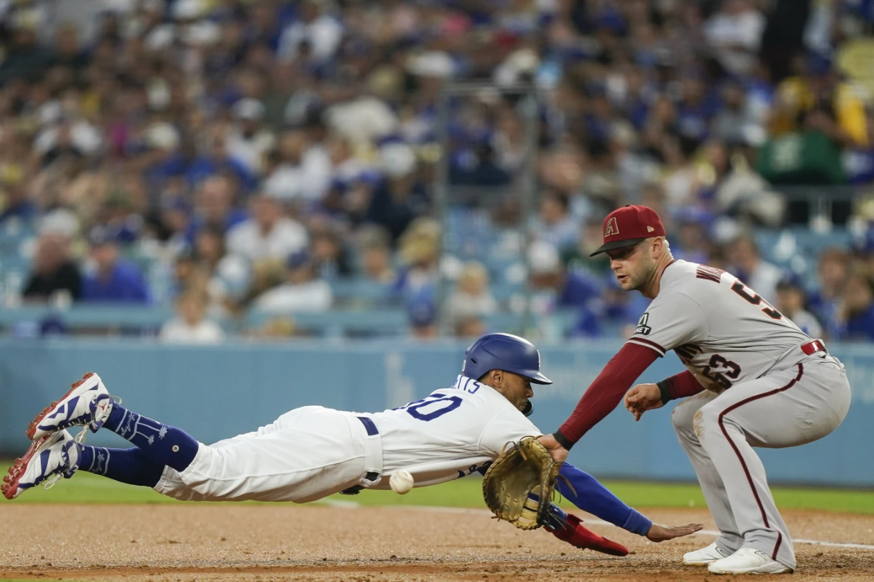 Los Angeles Dodgers’ Mookie Betts, left, dives back to first on a pickoff attempt as Arizona Diamondbacks first baseman Christian Walker waits for the throw during the first inning of a baseball game Tuesday, Aug. 29, 2023 in Los Angeles.