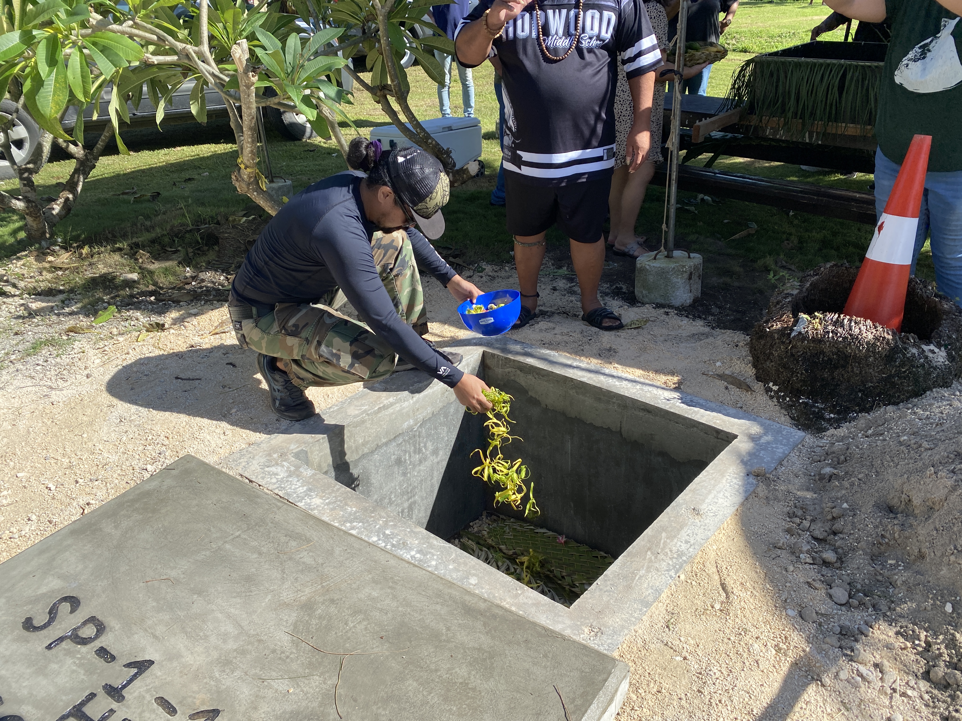 A DCCA staff member lays ylangylang on ancestral Chamorro remains.