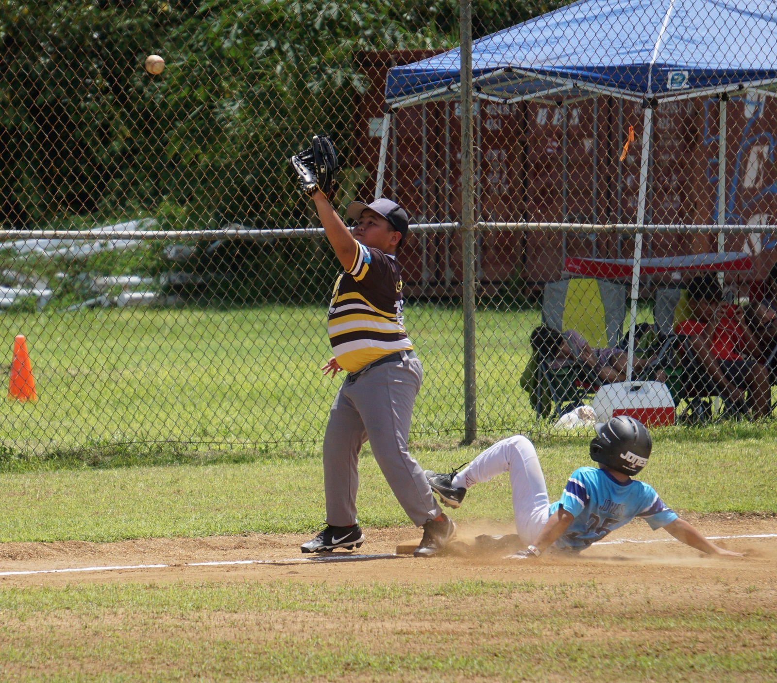 Toros third baseman Sky Lizama reaches for the catch as another player slides toward third base during a quarterfinal game of the 2023 Saipan Baseball League U12 Tournament on Saturday at the Miguel "Tan Ge" Pangelinan Baseball Field.