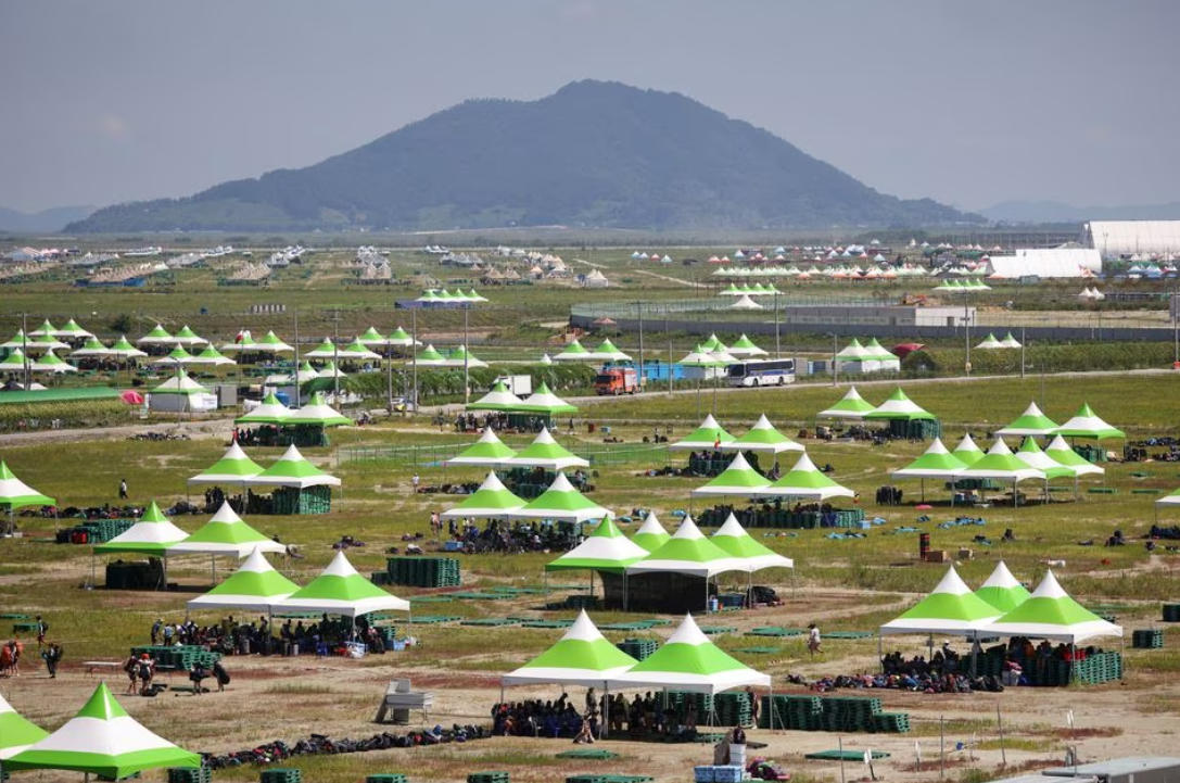 Participants gather under the shade as they prepare to leave the camping site of the 25th World Scout Jamboree in Buan, South Korea, Aug. 8, 2023.