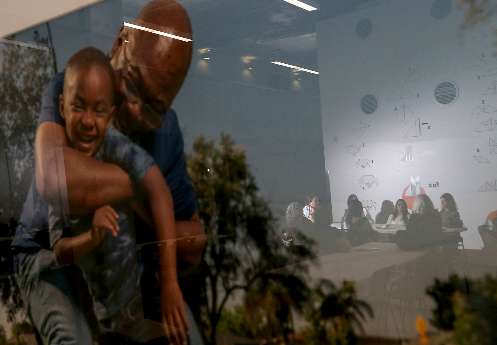 Staff members at Childrenâ€™s Institute in Los Angeles are reflected in a picture frame as they discuss the closure of a mental health program dedicated to linking vulnerable people to care. (Luis Sinco/Los Angeles Times/TNS)