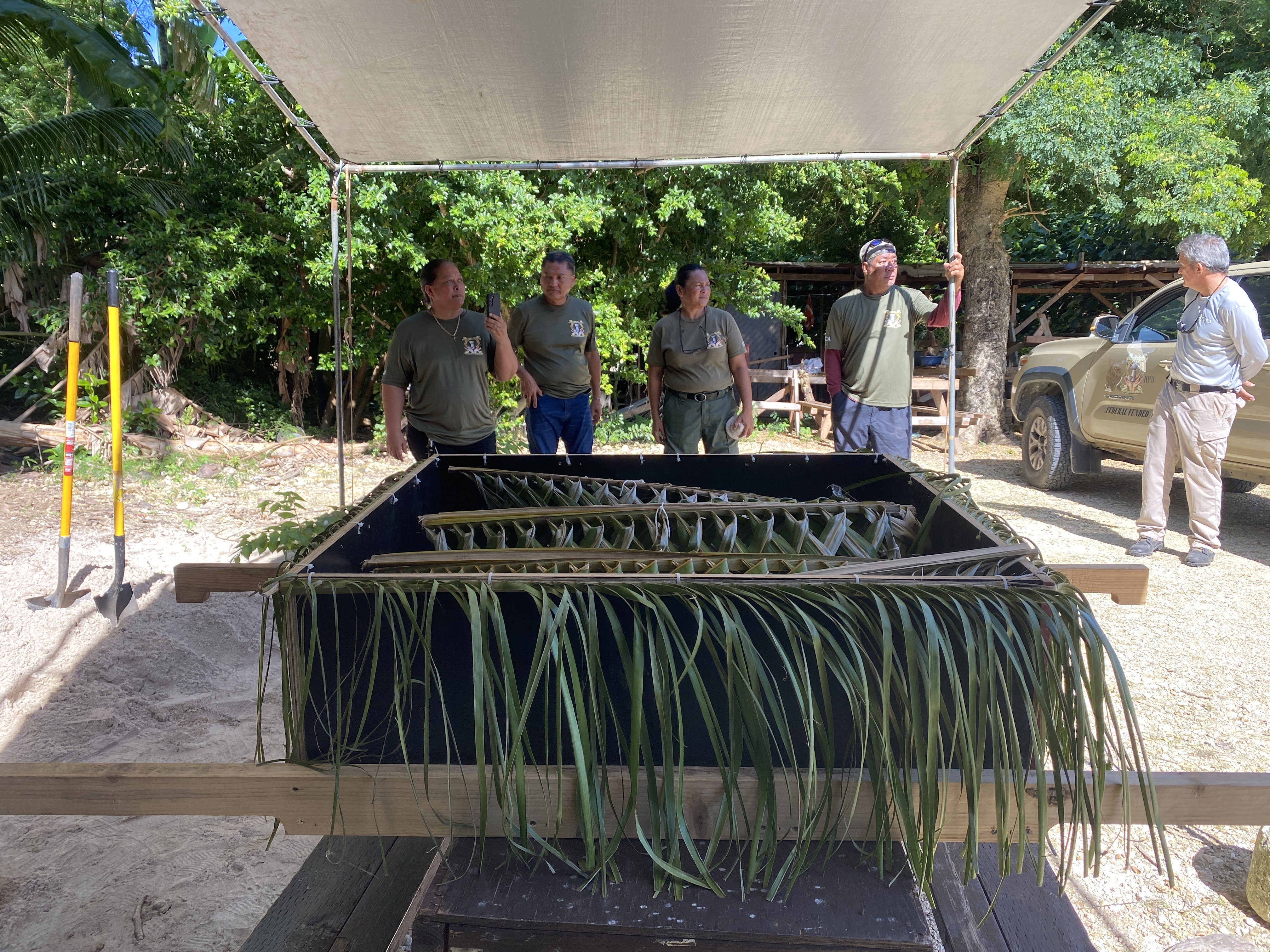 DCCA staff stand in the background as they wait to assist with the reinterment of ancestral Chamorro remains.