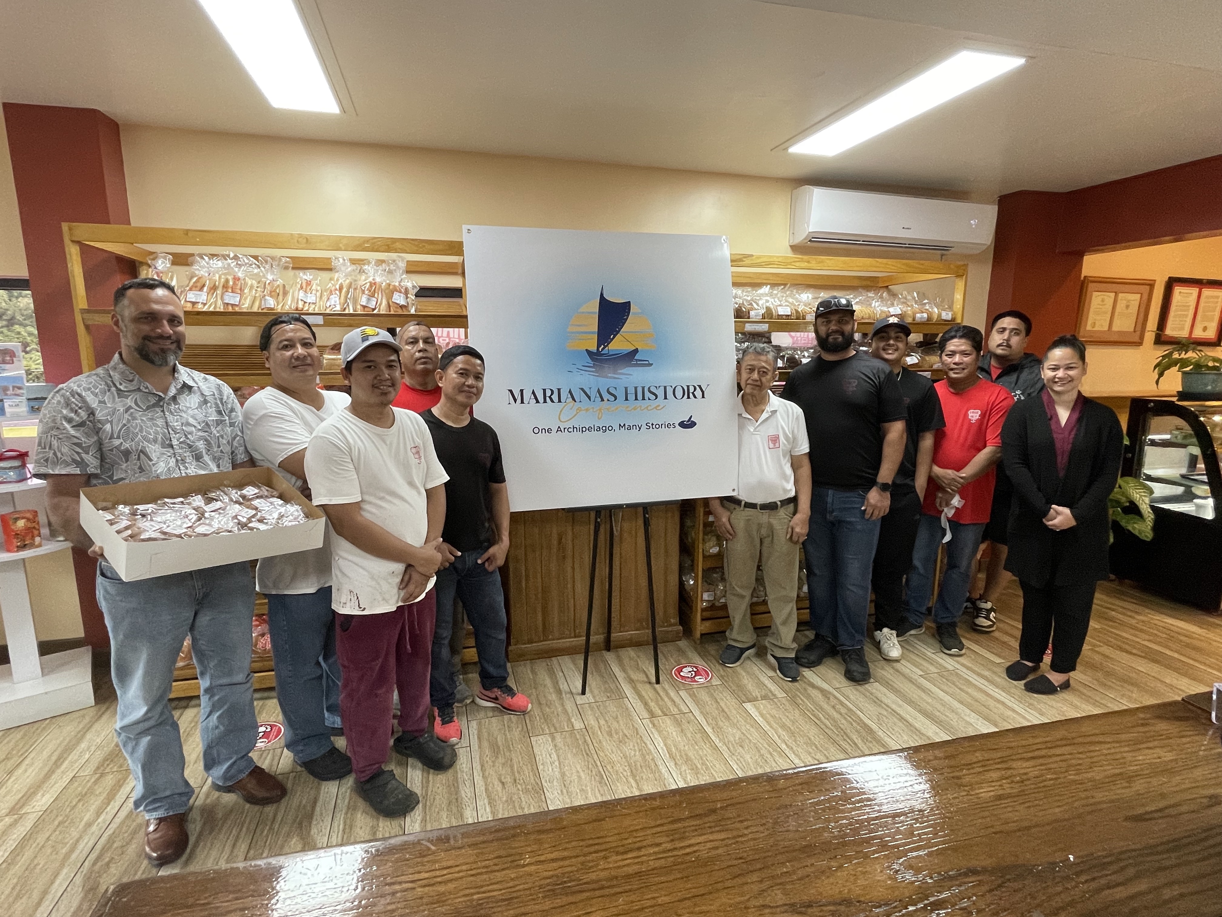 Northern Marianas Humanities Council Executive Director Leo Pangelinan, left, accepts an in-kind donation of 200 Chamorro Cookie packages from Herman's Modern Bakery for the 6th Marianas History Conference.