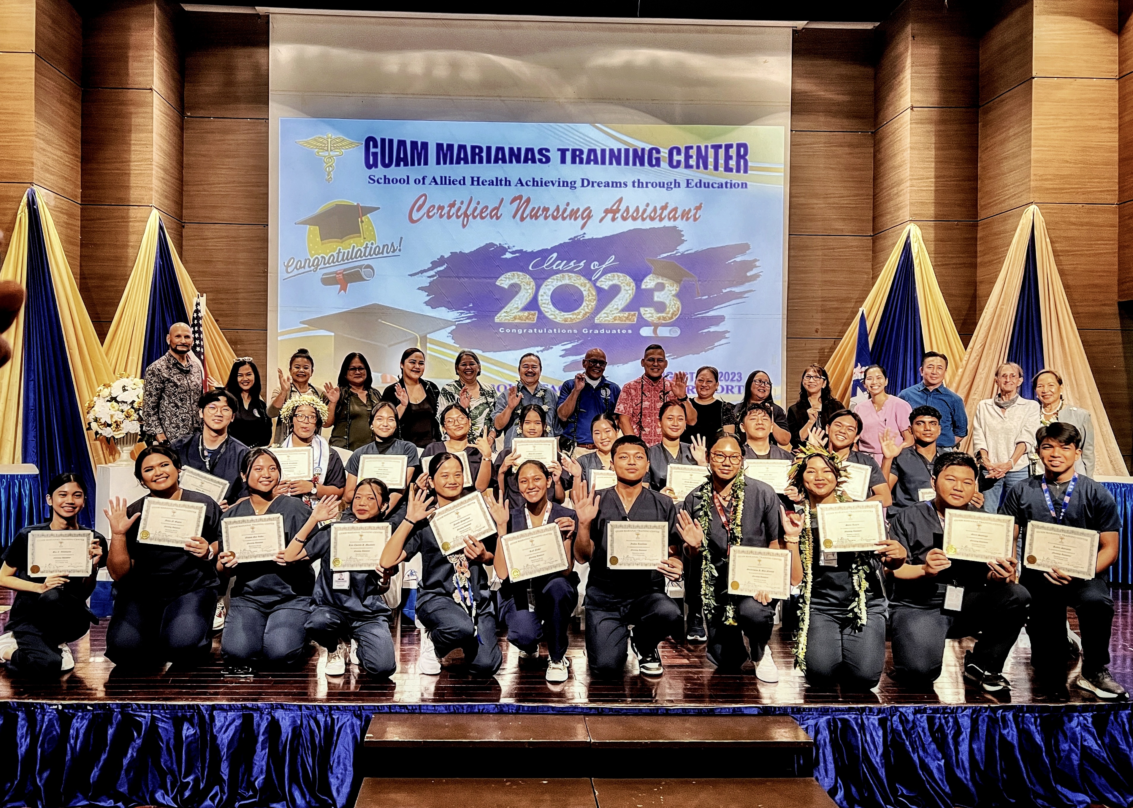 The 21 students who completed the Public School System-Guam Marianas Training Center Nursing Assistant Program show their certificates on Aug. 10, 2023 at Saipan World Resort. Also in photo are Commissioner of Education Dr. Alfred B. Ada, PSS-Career Technical and Education Program Director Dr. Jessica B. Taylor, GMTC President Fe Valencia-Ovalles, GMTC Executive Director Frankie L. Lake, Board of Education Vice Chairman Herman Atalig, Rita H. Inos Jr.-Sr. High School Acting Principal Annette Calvo, Tinian Jr.-Sr. High School Principal Lizbeth Perzinski, Special Assistant to the Commonwealth Healthcare Corp. CEO Janet Guerrero and Saipan Chamber of Commerce Executive Director Kimberly Camacho. Clinical instructors and instructors also honored the students.