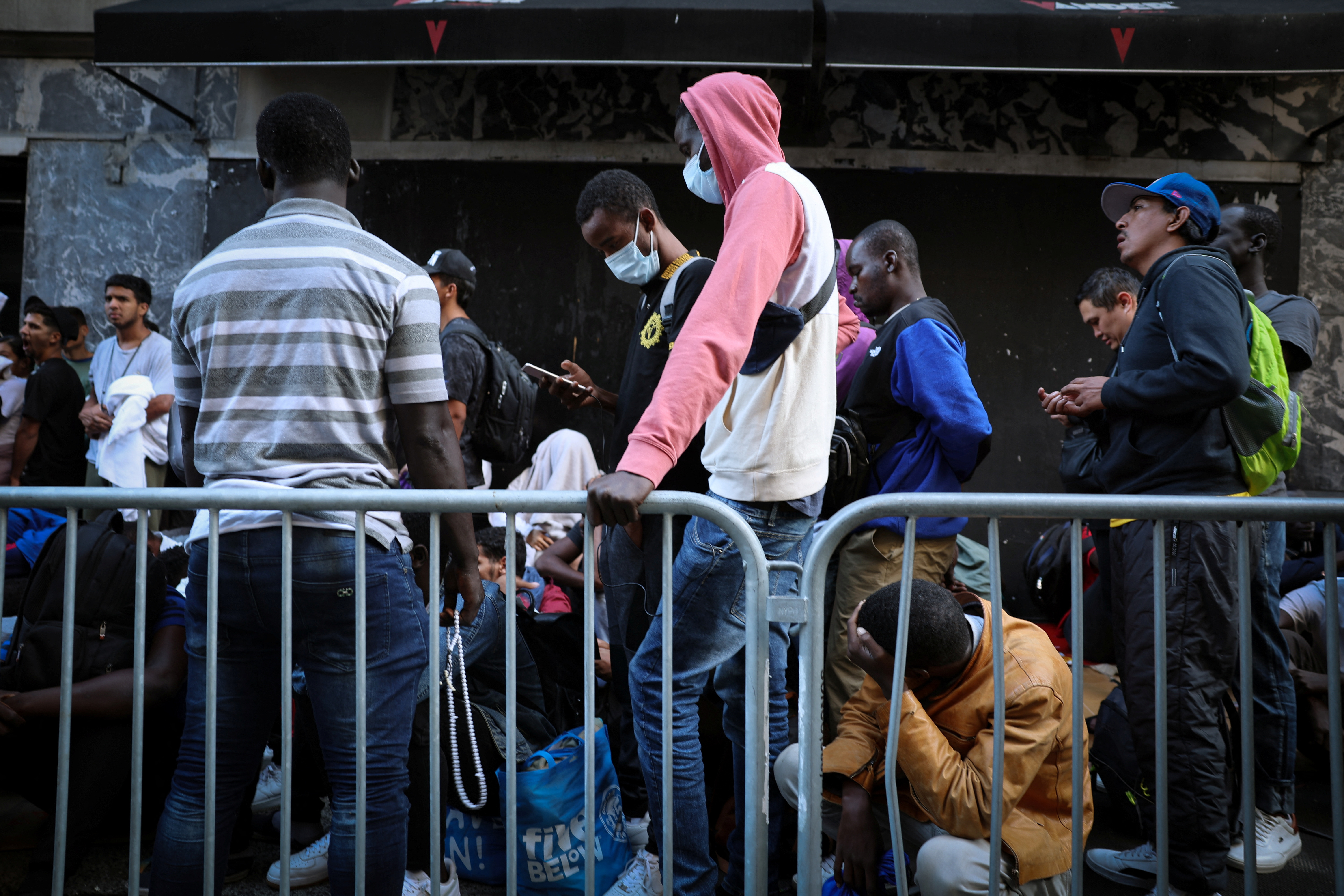 Recently arrived migrants to New York City wait on the sidewalk outside of the Roosevelt Hotel in midtown, Manhattan, where a temporary reception center has been established in New York City, New York, U.S., August 1, 2023. REUTERS/Mike Segar