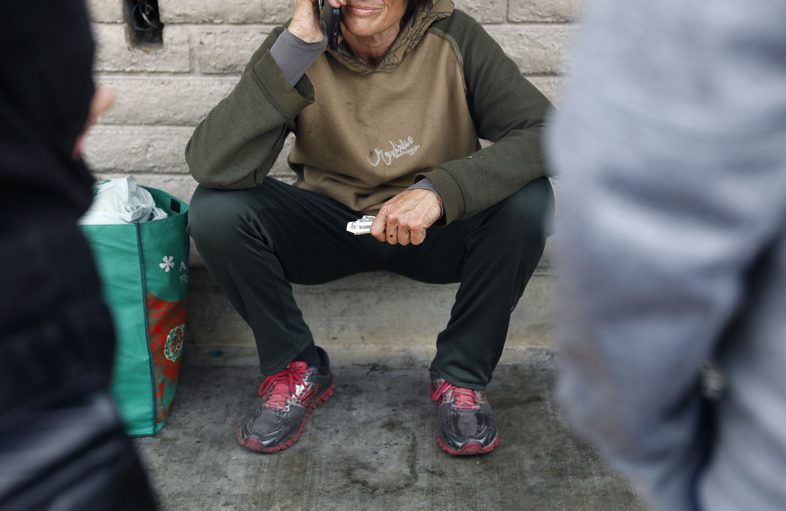 Sherry Hillâ€™s daughter talks to her mother on the phone outside of a convenience store, as Vicki Lucas, right, and Emily Spencer look on, in Pasadena, California, on May 11, 2023. (Christina House/Los Angeles Times/TNS)