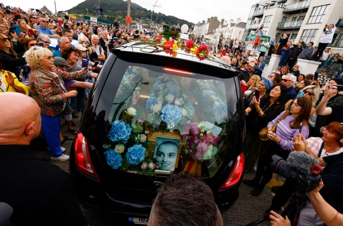 A hearse carrying the coffin of late Irish singer Sinead O'Connor passes by during her funeral procession where fans line the street to say their last goodbye to her, in Bray, Ireland, Aug. 8, 2023.