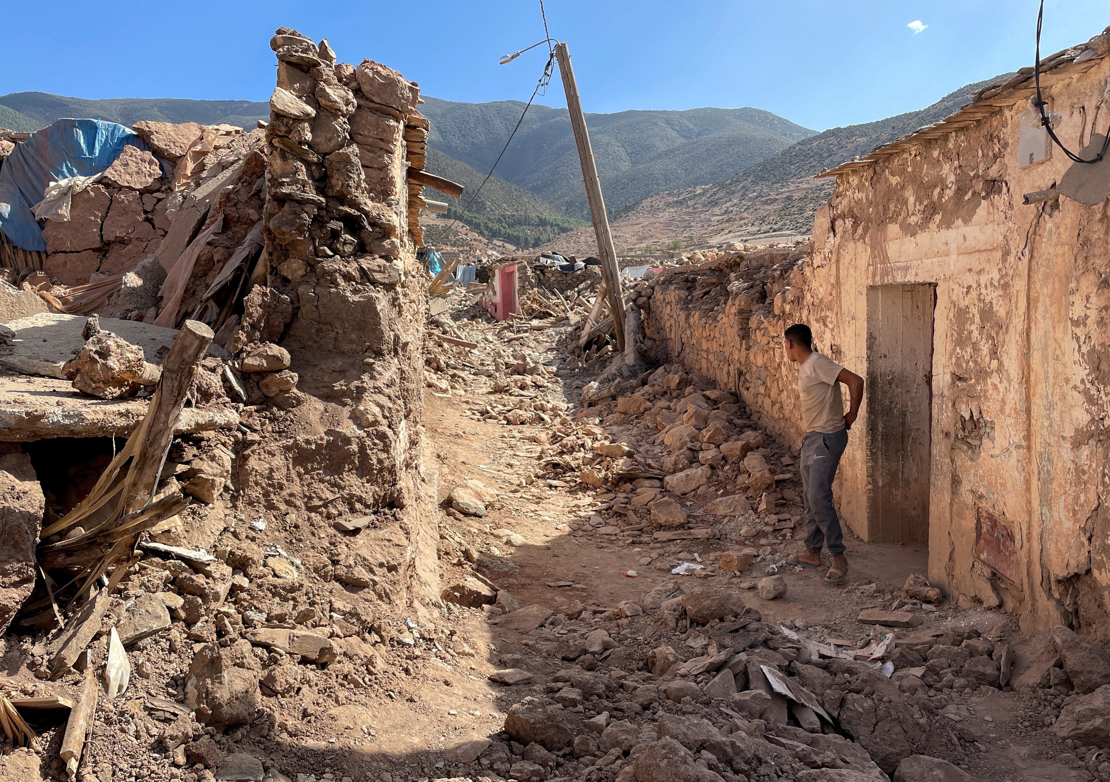 A person stands near damaged houses in Tafeghaghte, a remote village of the High Atlas mountains, following a powerful earthquake in Morocco, September 10, 2023. REUTERS/Ahmed El Jechtimi