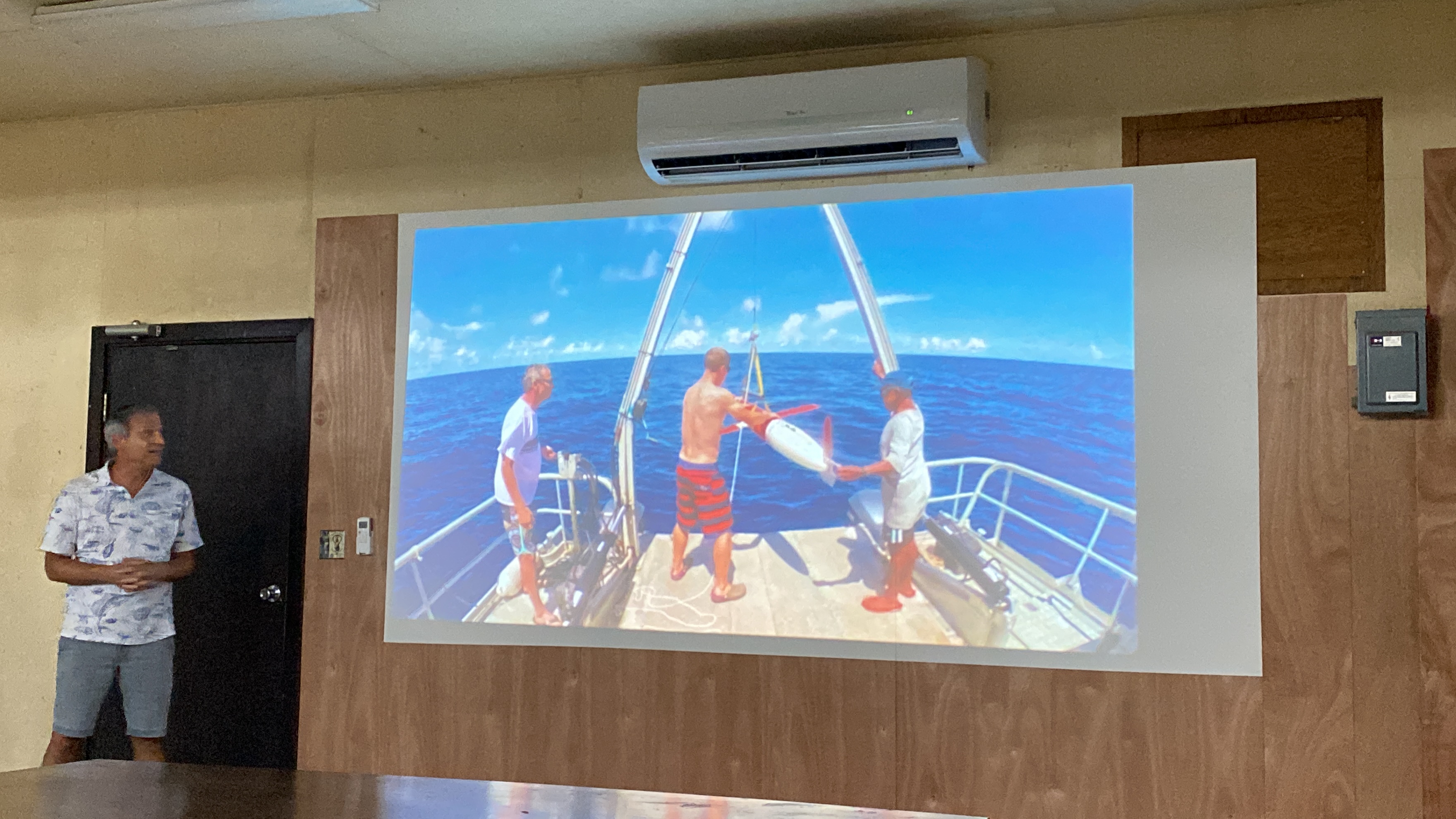 Professor Dan Rudnick, a professor at UC San Diego. Behind him is a photo displaying how they lower ocean gliders into the Western Pacific to conduct studies of undercurrents.