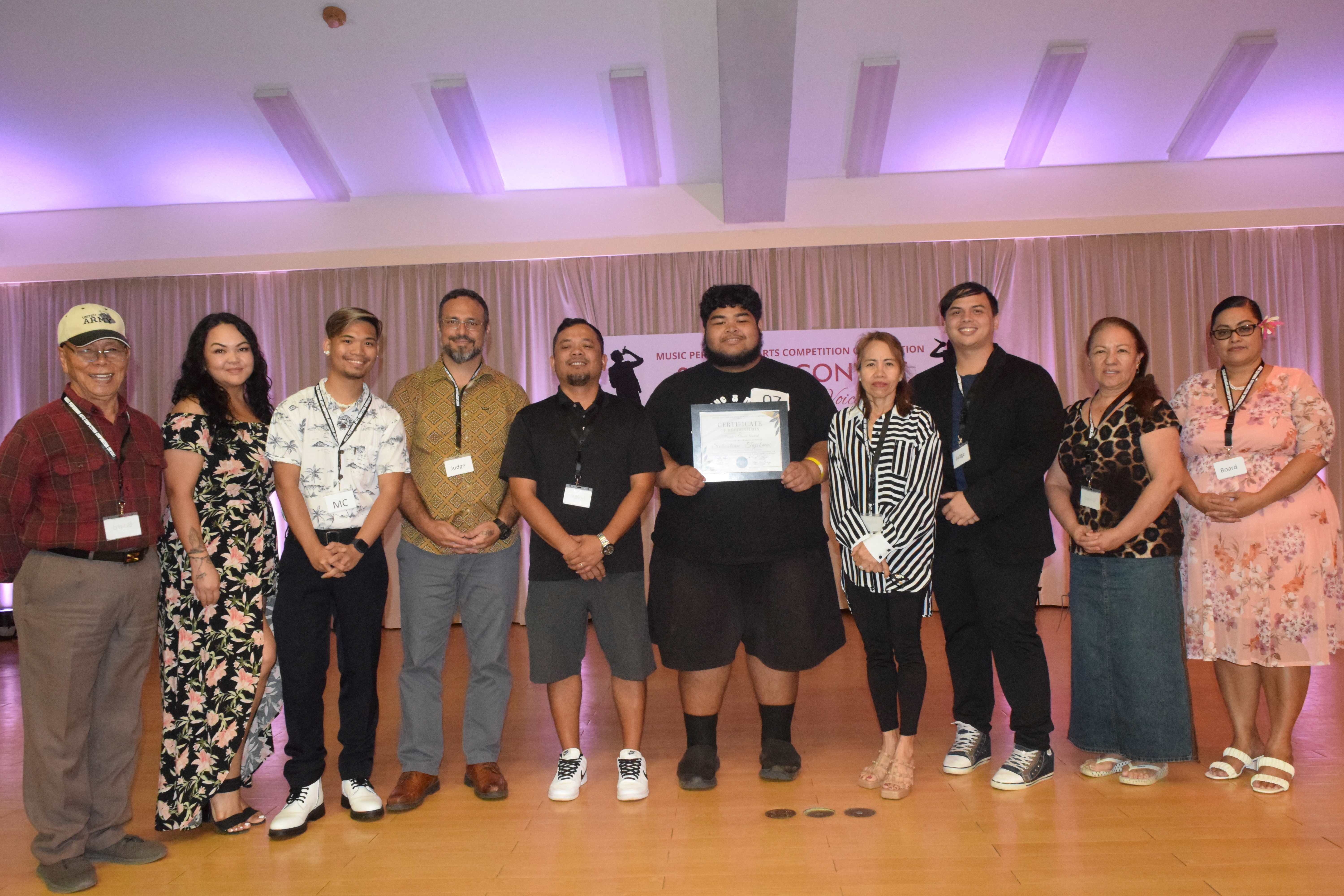 Sebastian Tajibmai, center, holds his People's Choice Award as he poses for a photo with Music Performing Arts Competition Corp. officers and competition judges.