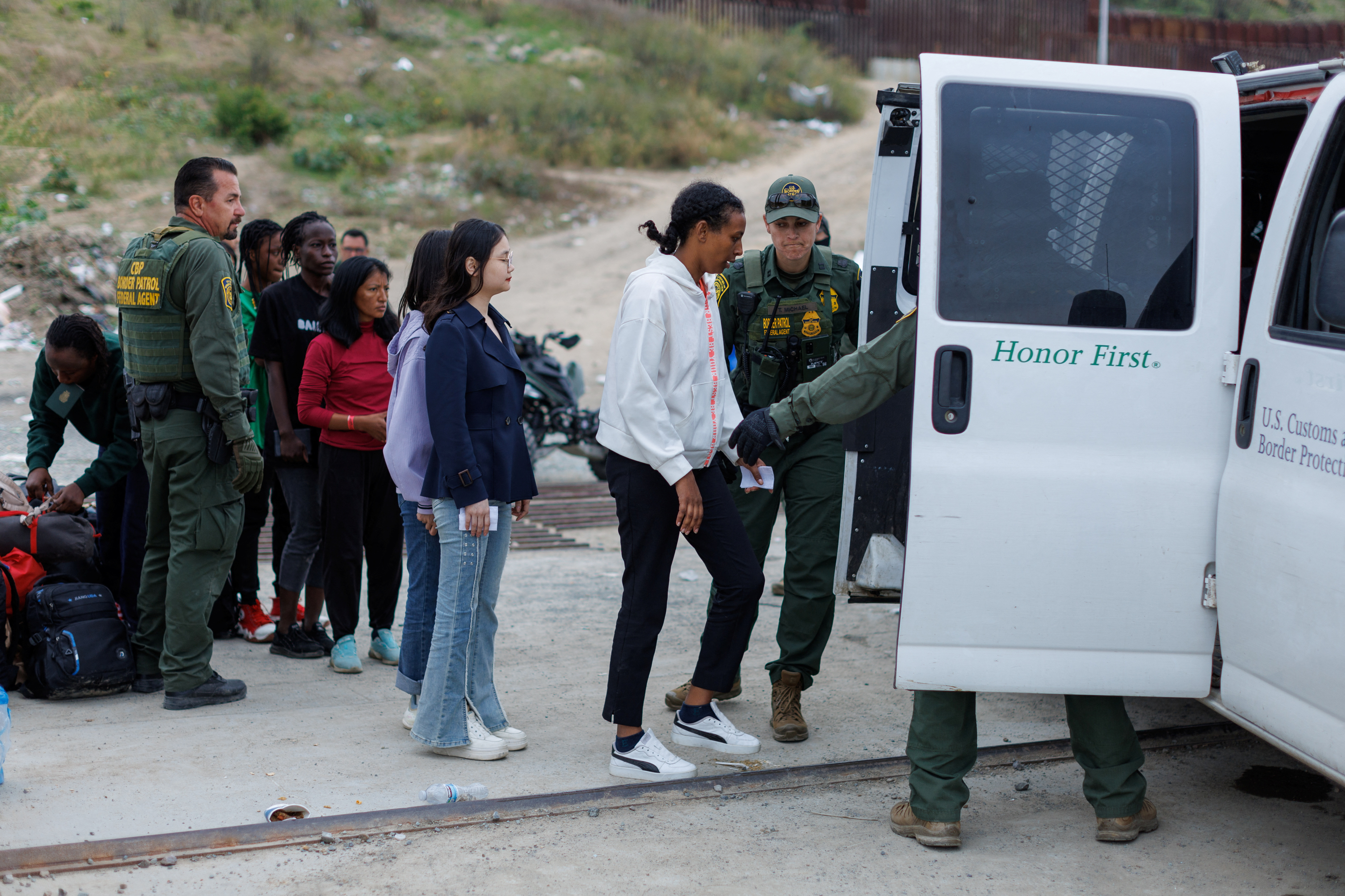 Migrants who had gathered between the primary and secondary border fences between Mexico and the United States are loaded into a van by U.S. customs and border patrol for processing by U.S immigration in San Diego, U.S., September 14, 2023. 