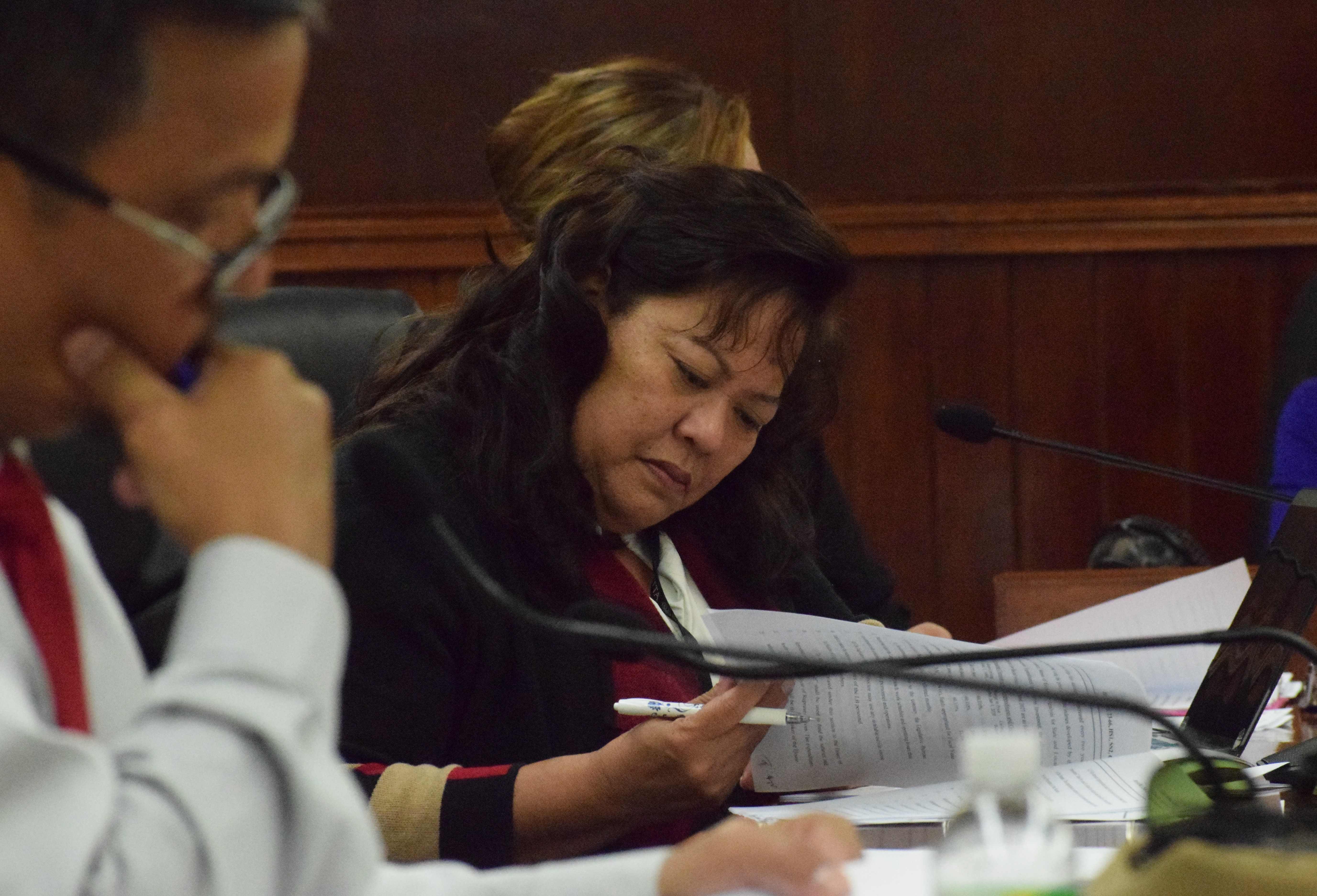 Sens. Jude Hofschneider and  Celina Babauta review their copies of the conference committee report  on the fiscal year 2024 budget during a session on Monday.