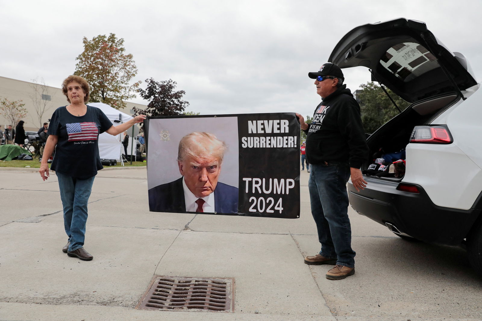 People hold a banner featuring former U.S. President and Republican presidential candidate Donald Trump, in Clinton Township, Michigan. U.S., September 27, 2023. 
