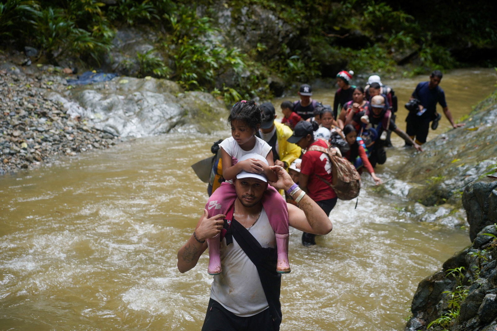 A migrant carries a child as they along with others continue their journey to the U.S. border, in Acandi, Colombia July 9, 2023. 