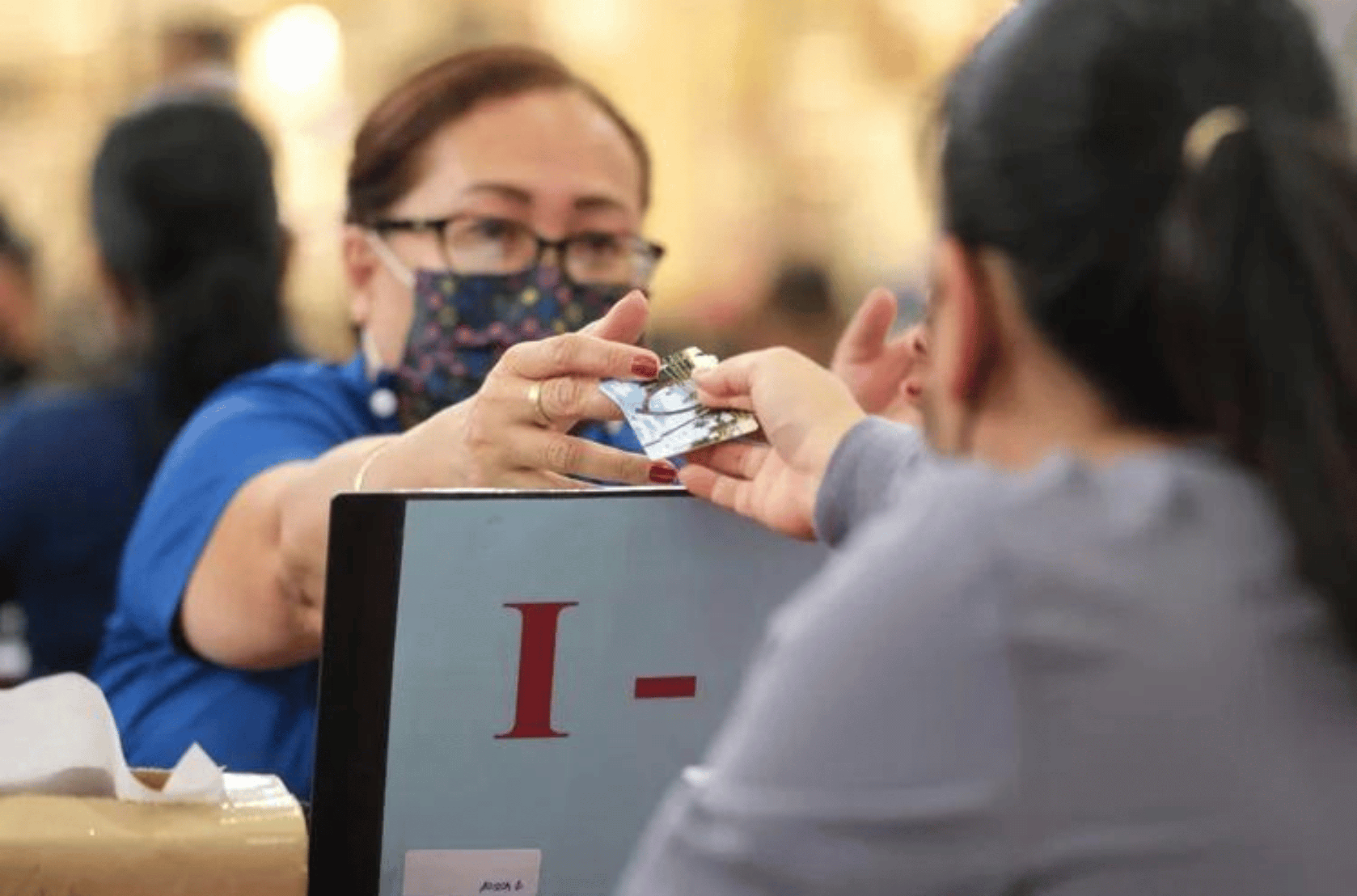 Department of Public Health and Social Services Claims Specialist Annie Caseres issues Pandemic Electronic Benefit Transfer cards to an applicant at the Micronesia Mall center court.