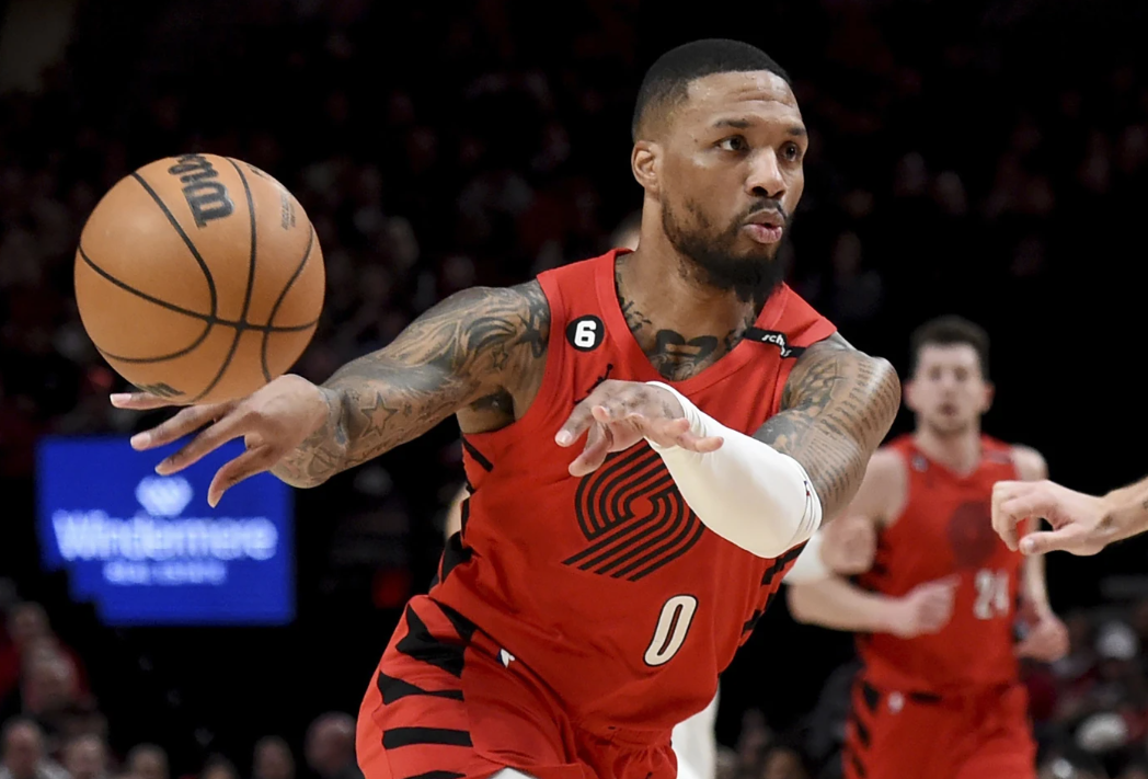 Portland Trail Blazers guard Damian Lillard, left, passes the ball against the Washington Wizards during the first half of an NBA basketball game in Portland, Ore., Feb. 14, 2023.