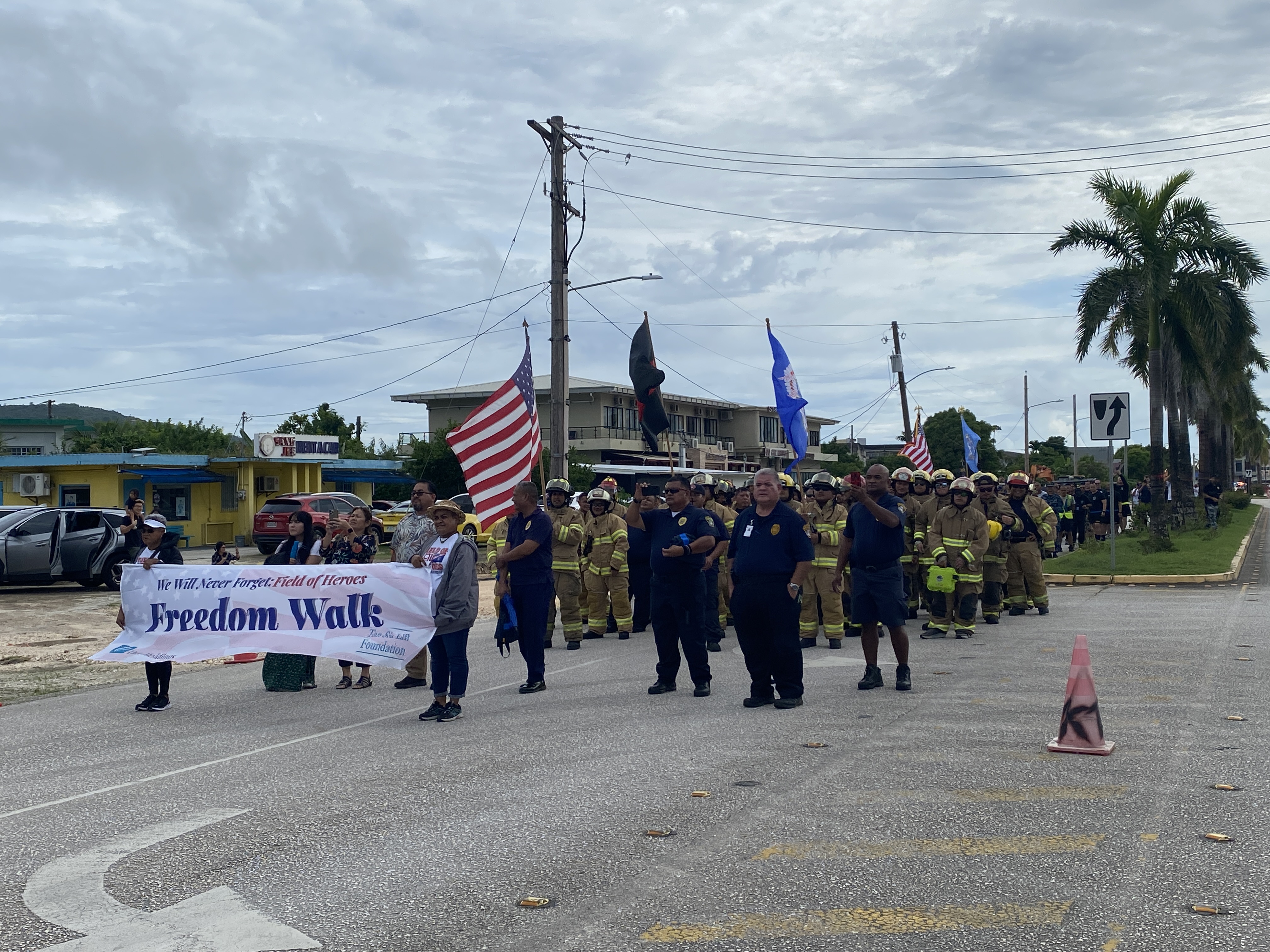 Marchers watch as the color guard is saluted by fire hoses.